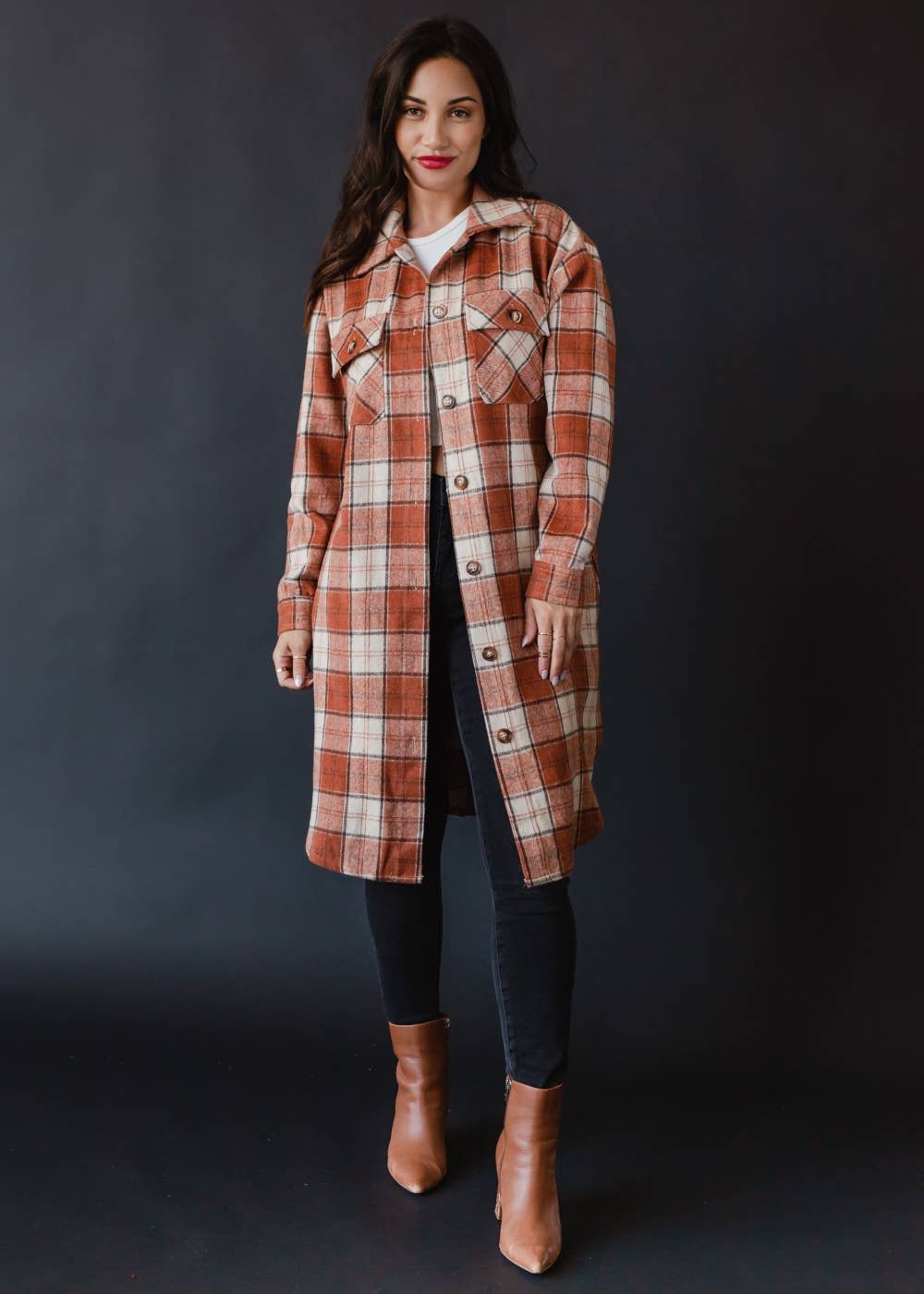 Woman wearing a plaid coat against a dark background