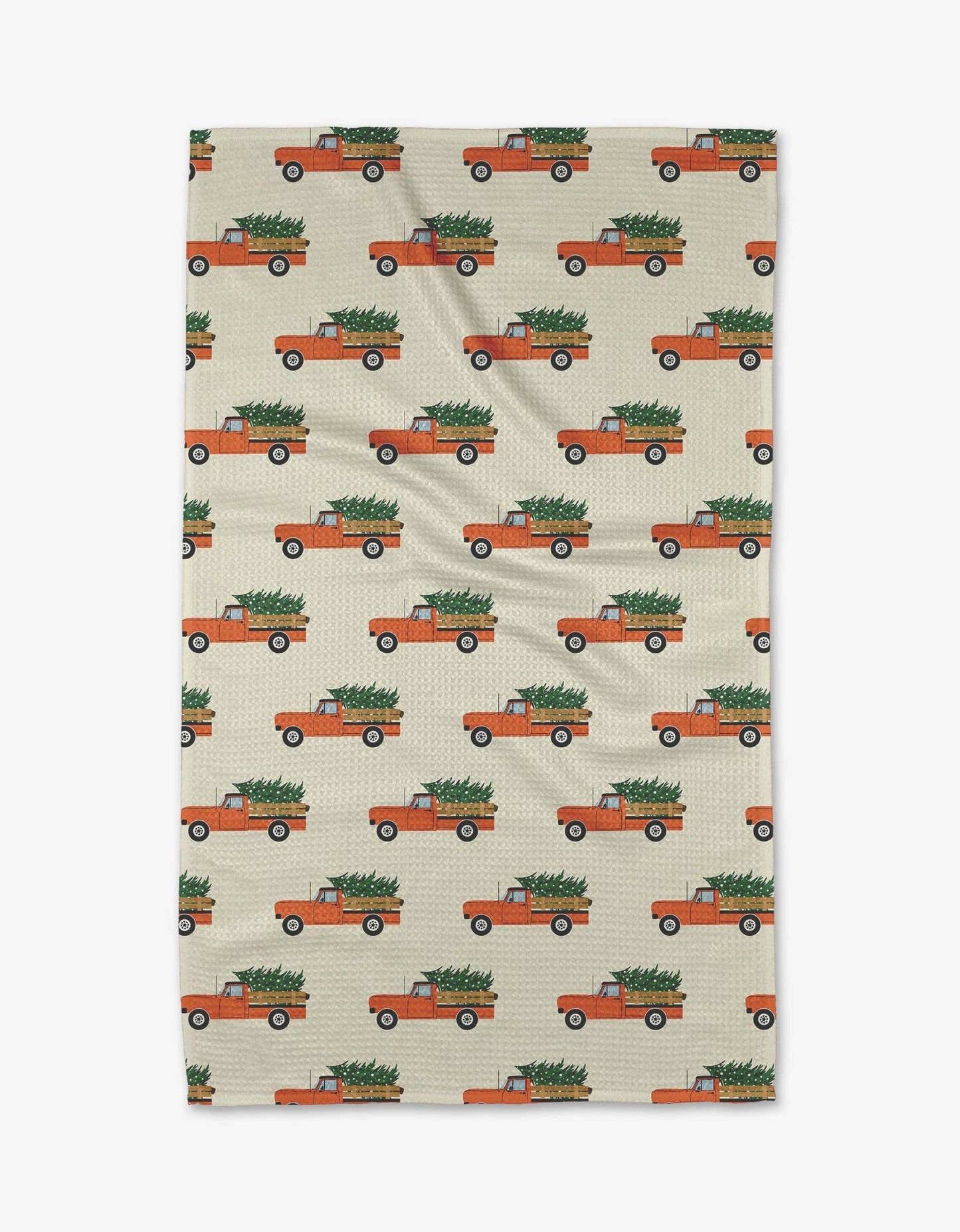 Geometry Tea Towel Christmas Ride Patterned towel with orange trucks carrying Christmas trees on a beige background