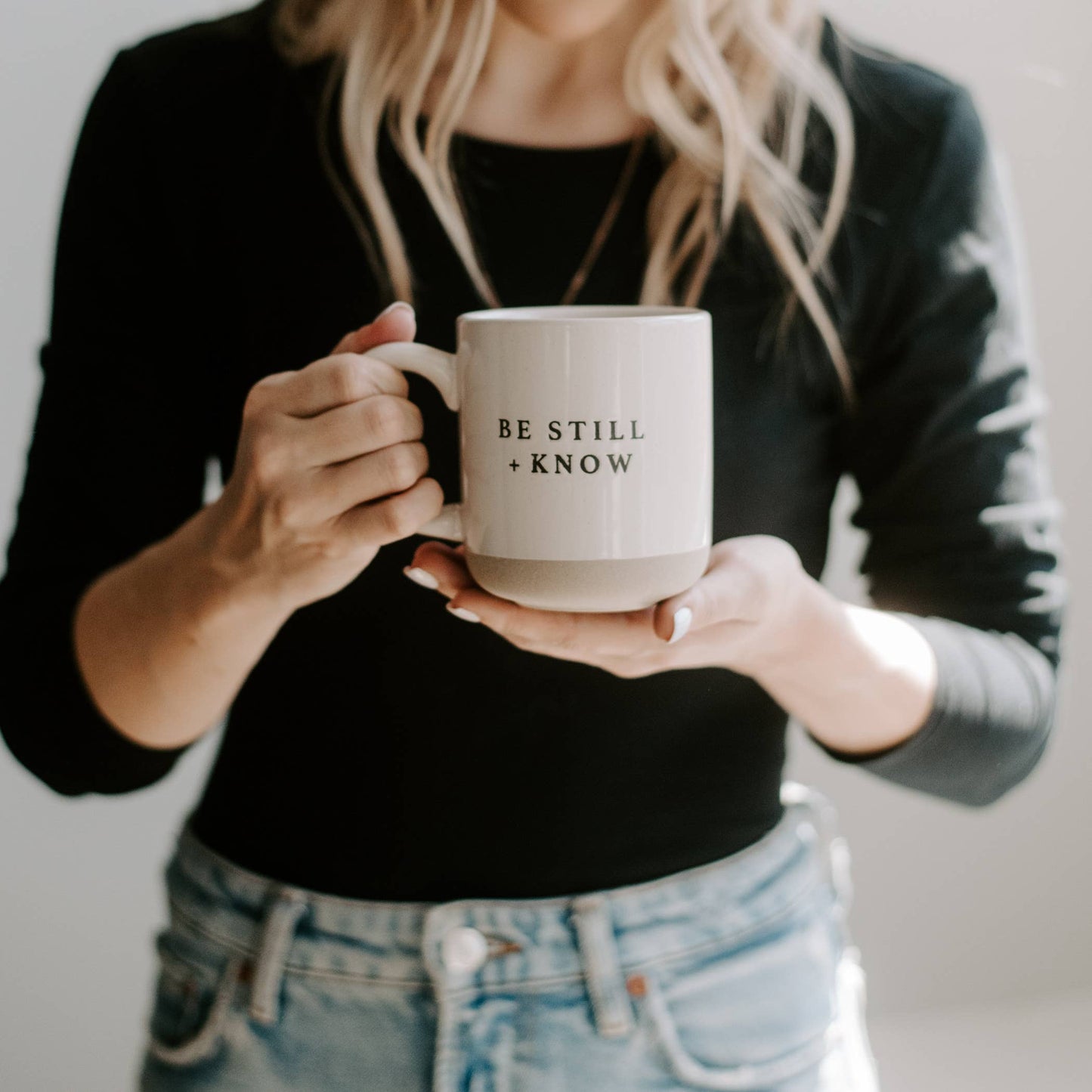 Person holding a mug with 'Be Still + Know' text