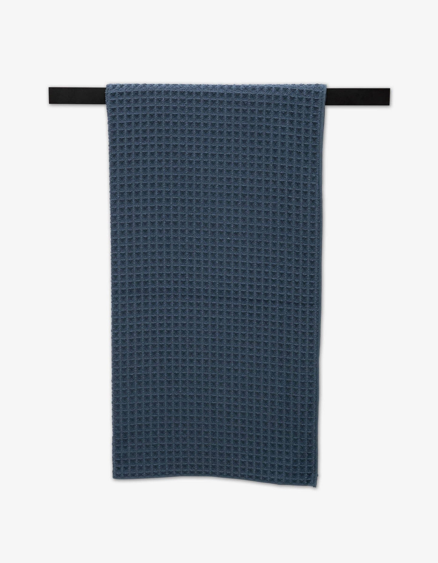 Geometry Waffle Bath Towel Midnight Blue waffle-textured towel hanging on a black rod against a white background
