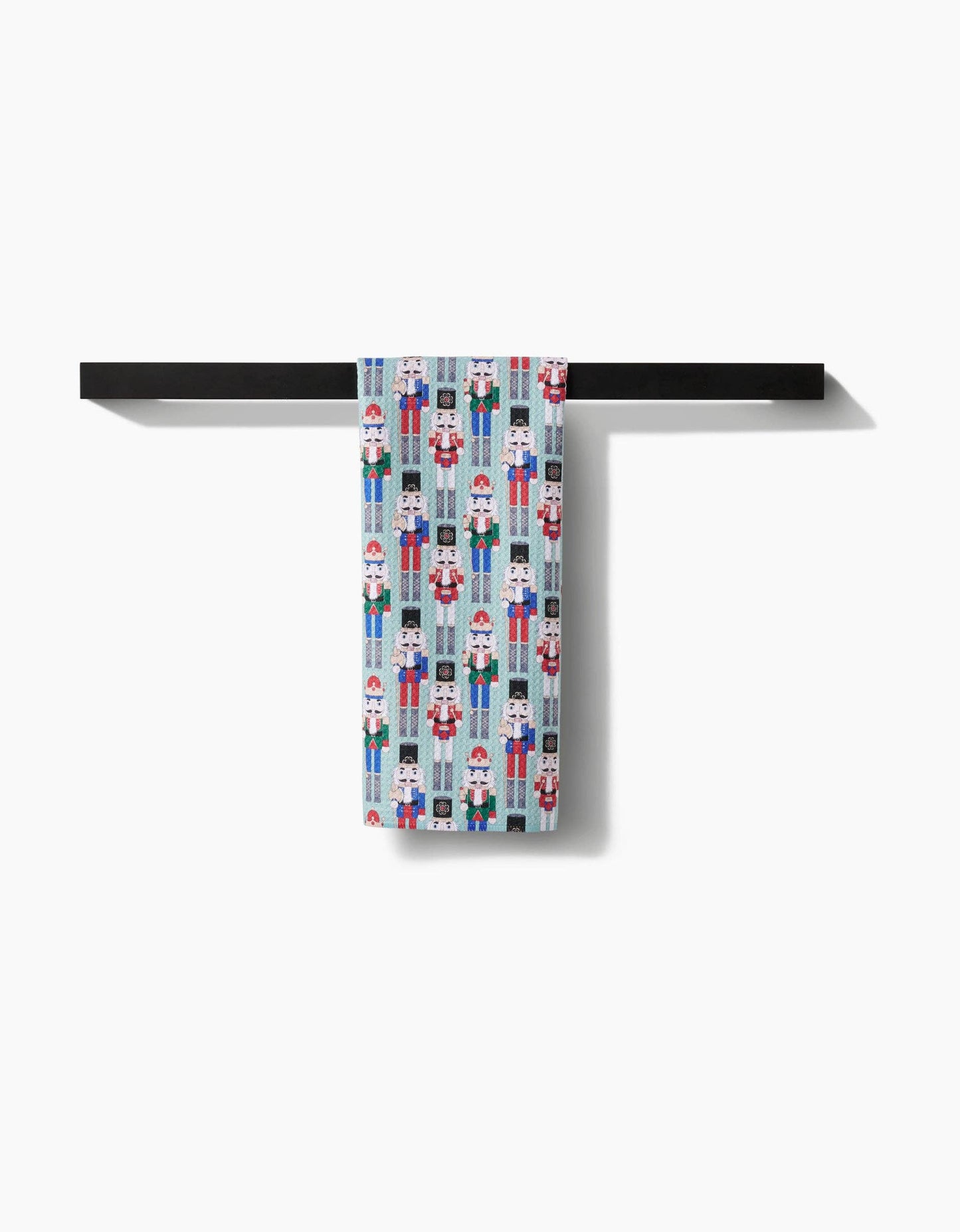 Geometry Tea Towel with nutcracker pattern hanging on a black towel rack against a white background