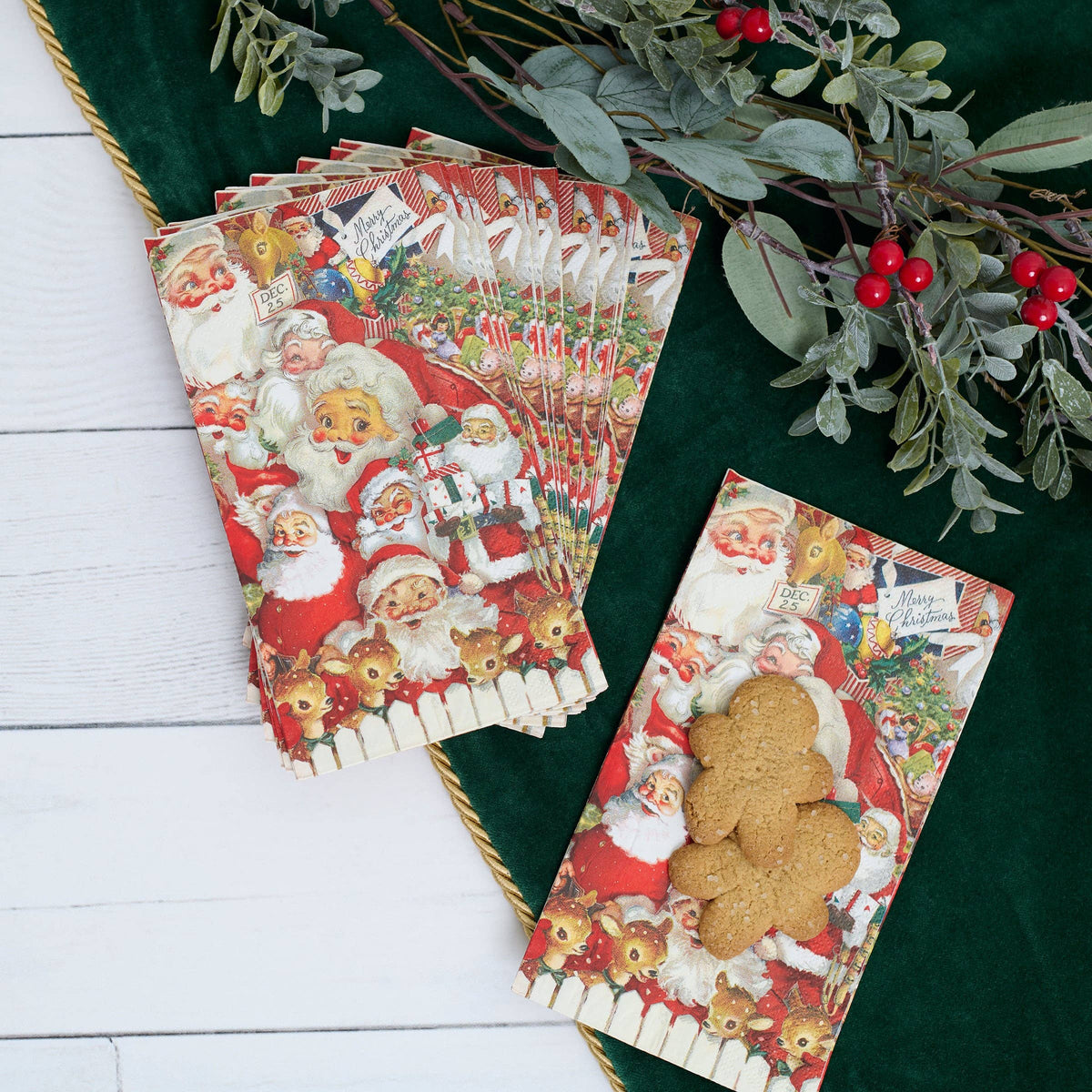 Set of Christmas-themed paper napkins with Santa Claus and gingerbread design on a green surface with foliage.
