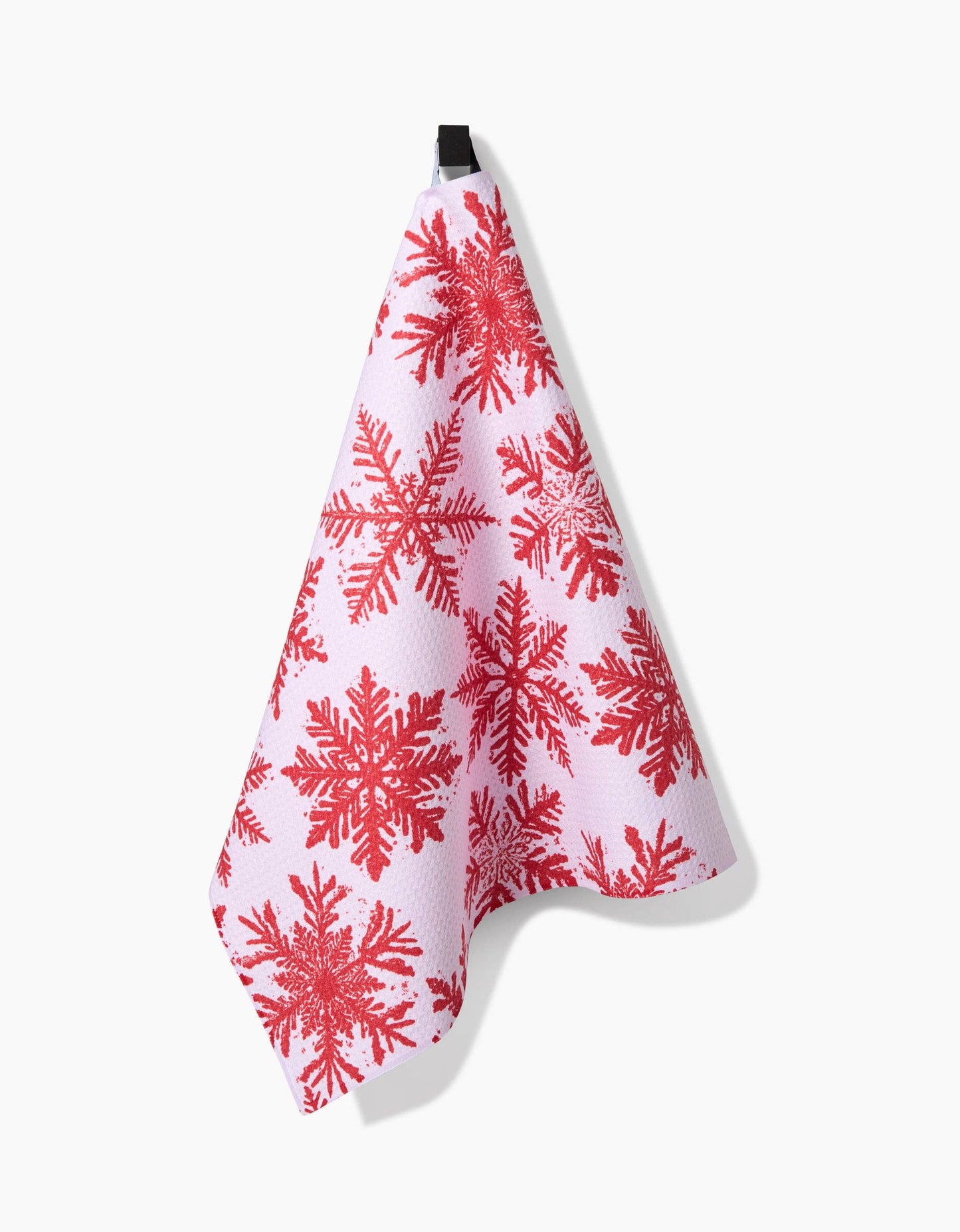 White towel with red snowflake pattern hanging on a white background
