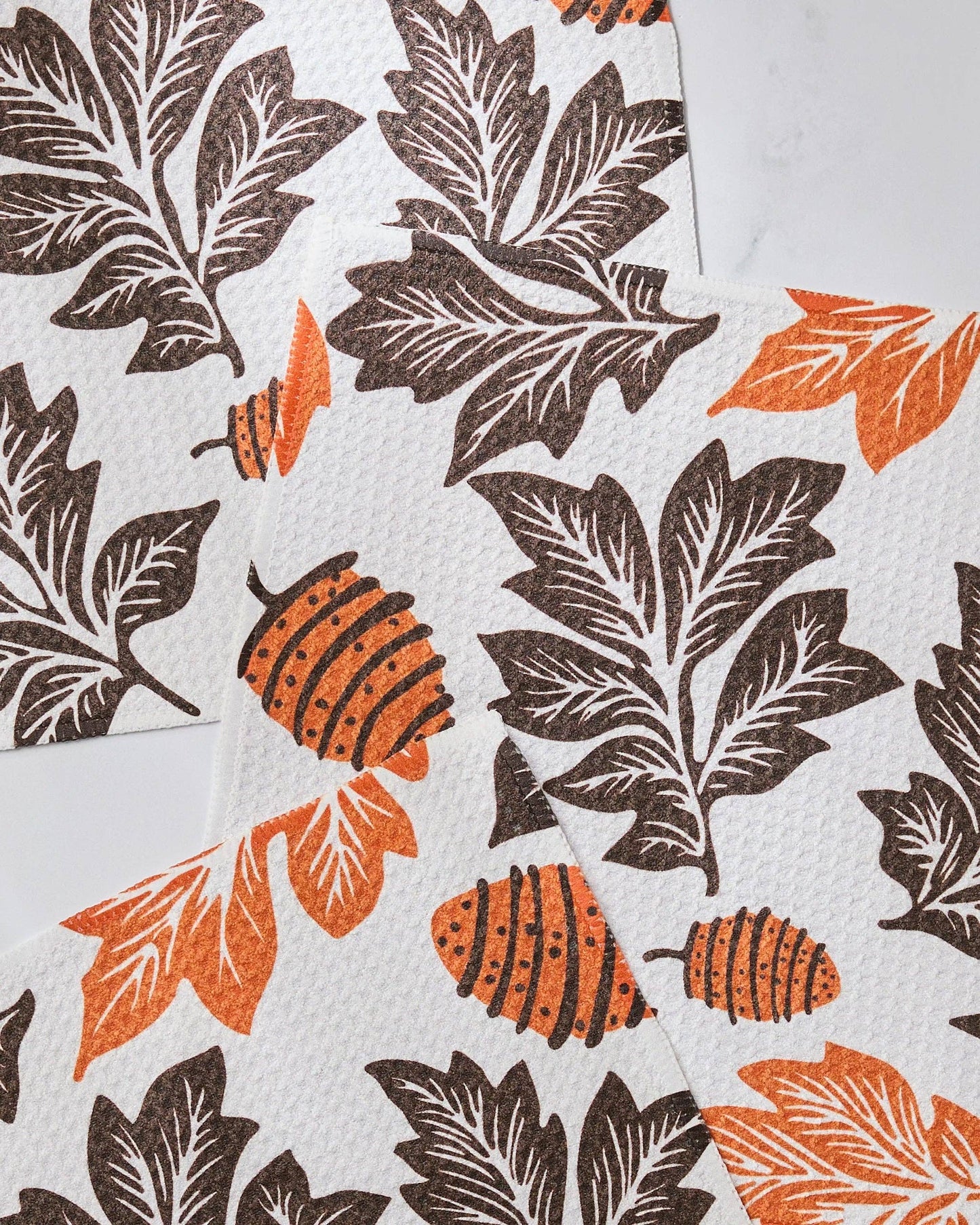 Patterned fall themed dishcloth set with brown and orange leaves on a white background Geometry brand