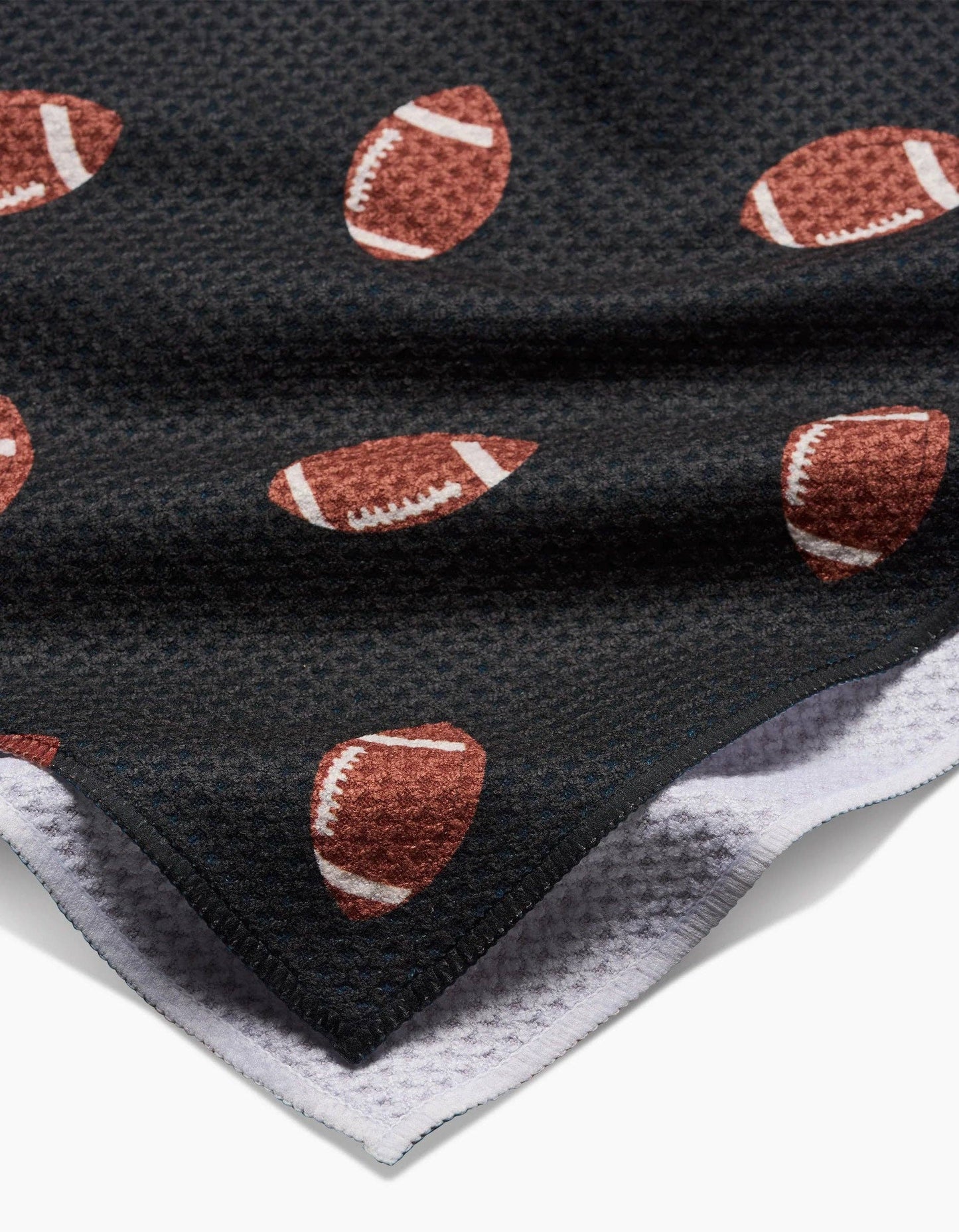 Black Geometry brand kitchen tea towel with brown football pattern on a white background