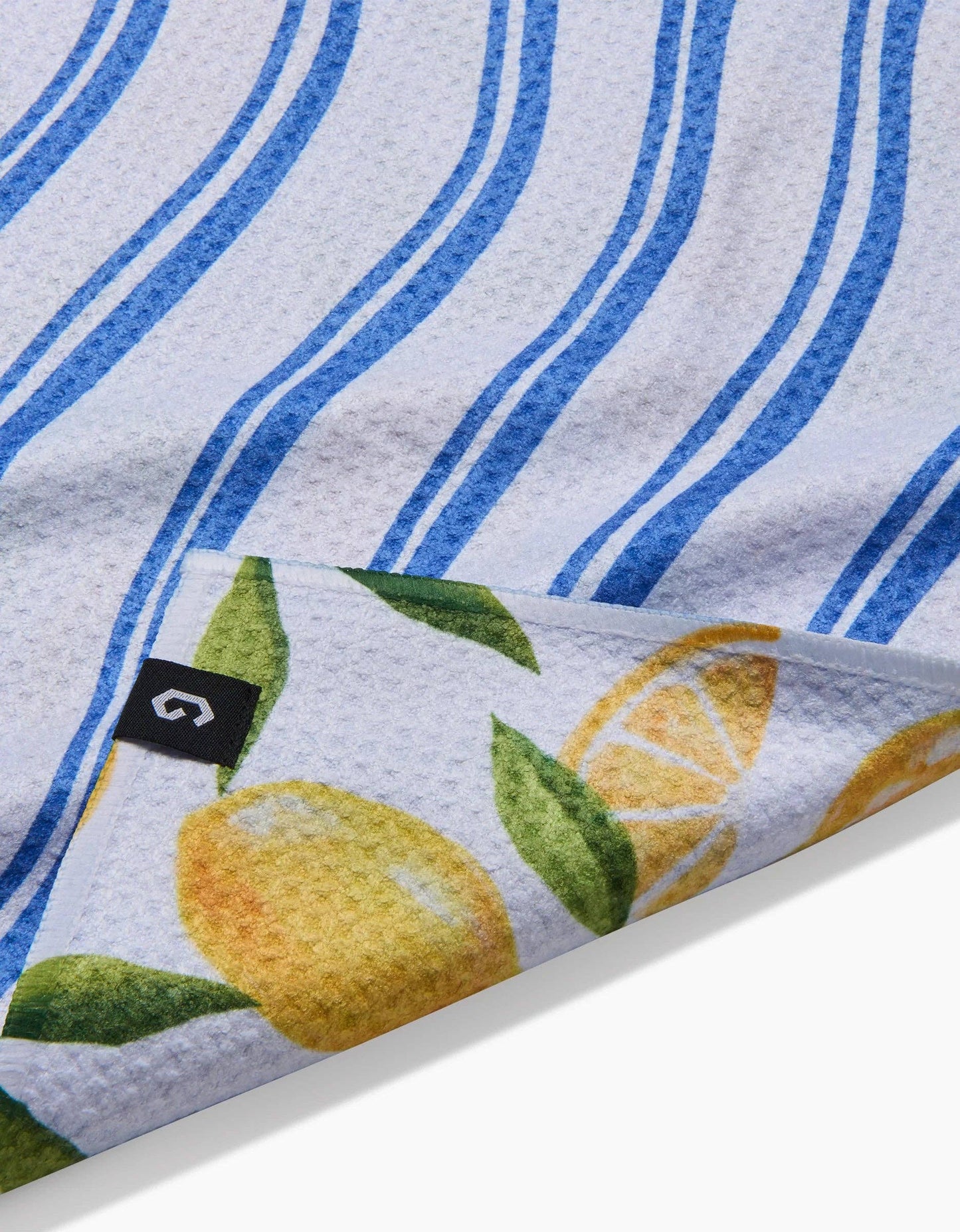 Kitchen towel with lemon design and blue stripes, featuring a brand logo.