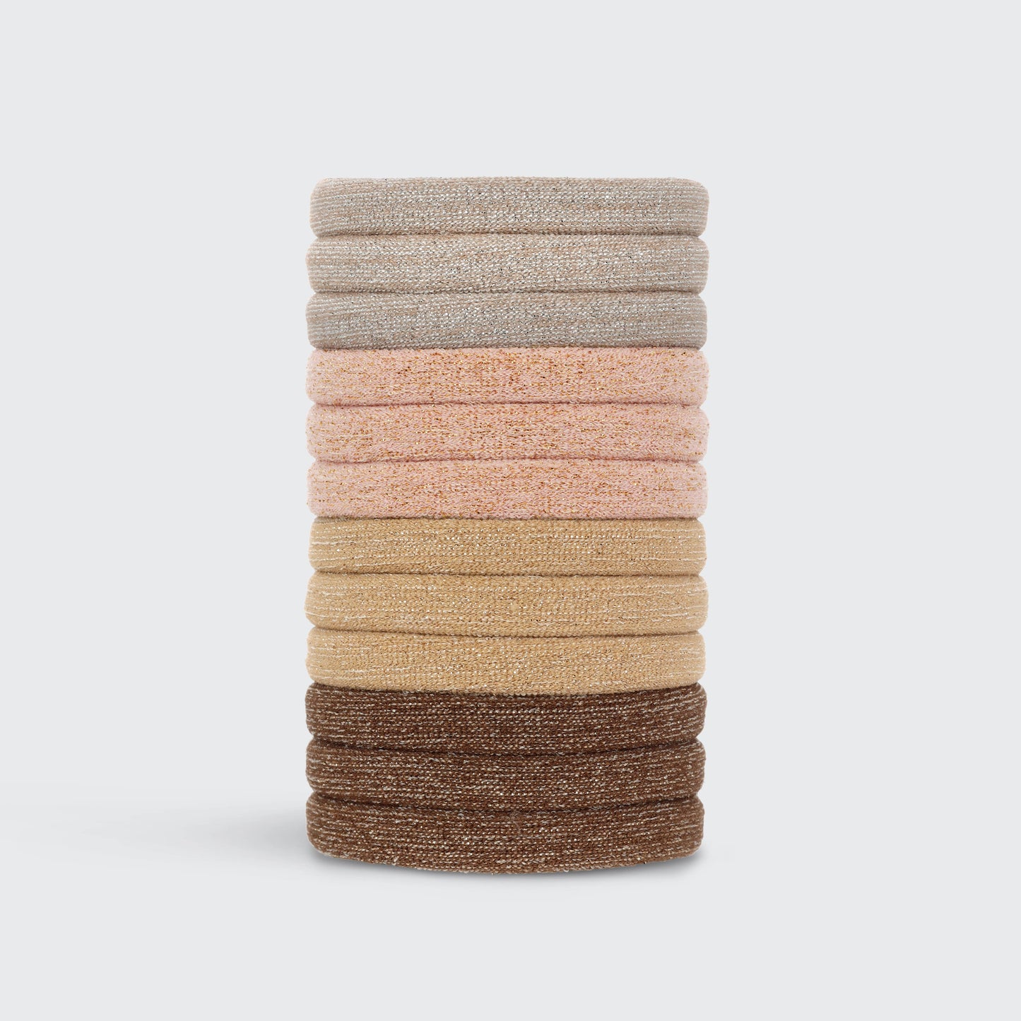 A collection of Kitsch brand glittery nylon hair elastics in various neutral shades, displayed both in a stack and in packaging.