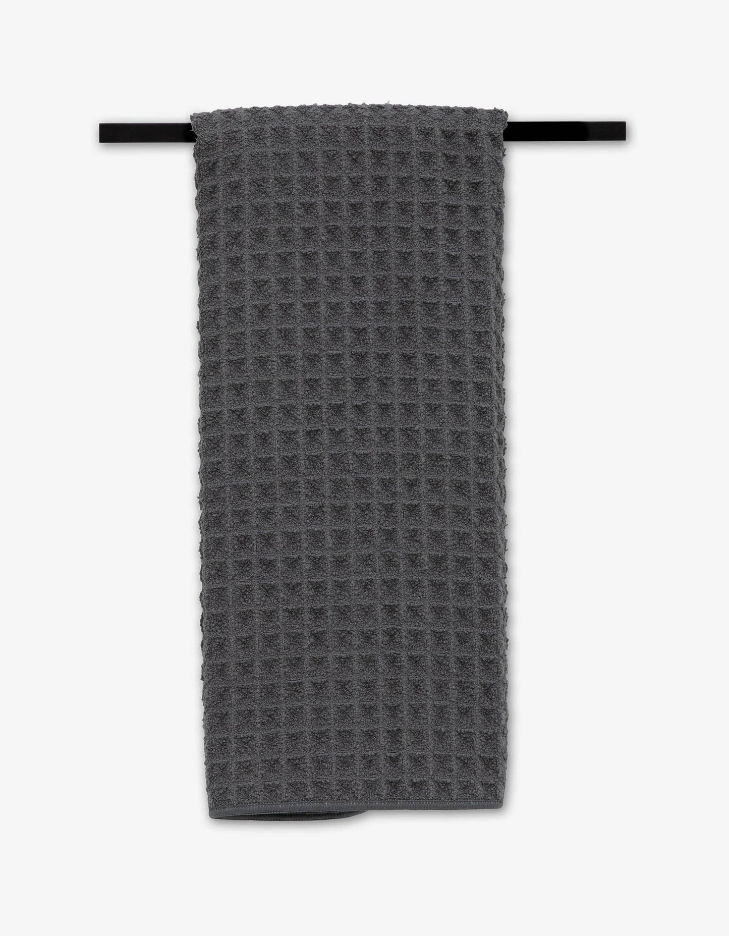 Gray waffle-textured towel hanging on a black rod against a white background Geometry brand