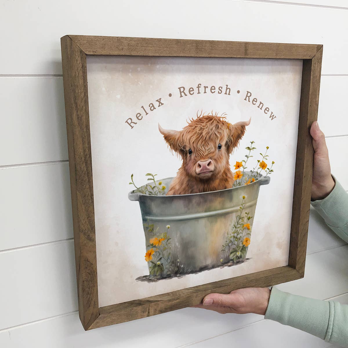Framed artwork with a cow in a bathtub and 'Relax Refresh Renew' text.