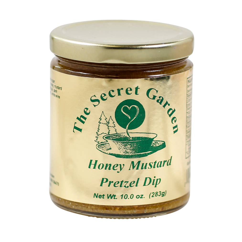 A glass jar of The Secret Garden Honey Mustard Pretzel Dip with a gold-colored metal lid and a beige label with green text and graphics, set against a plain white background.