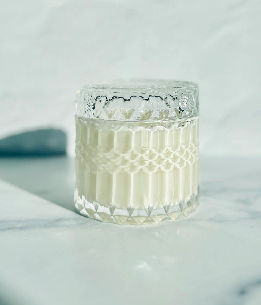 Clear glass candle with textured design on a light gray background