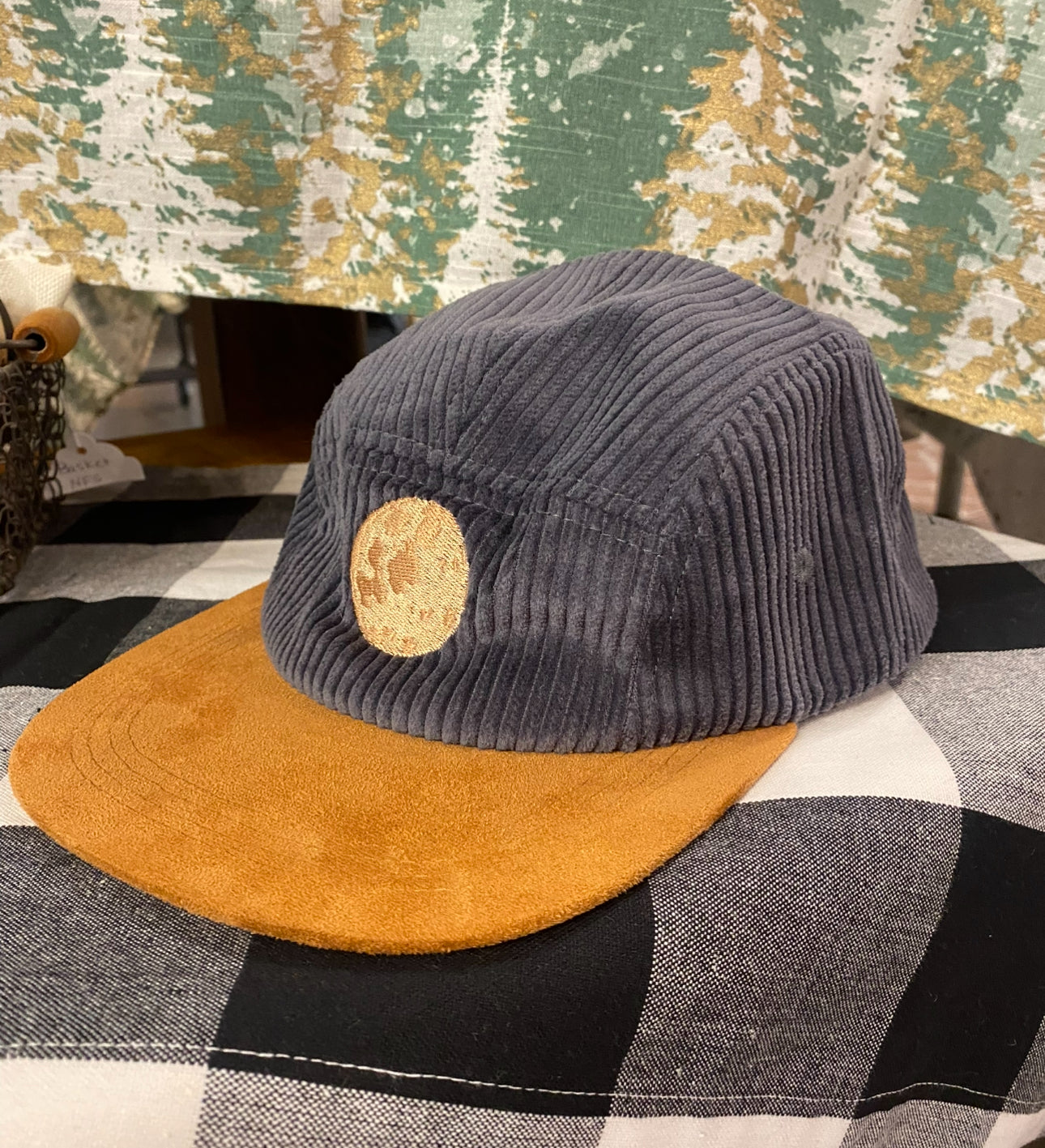 Gray Courduroy Hat with Moon Embroidery on black and white table with tree background