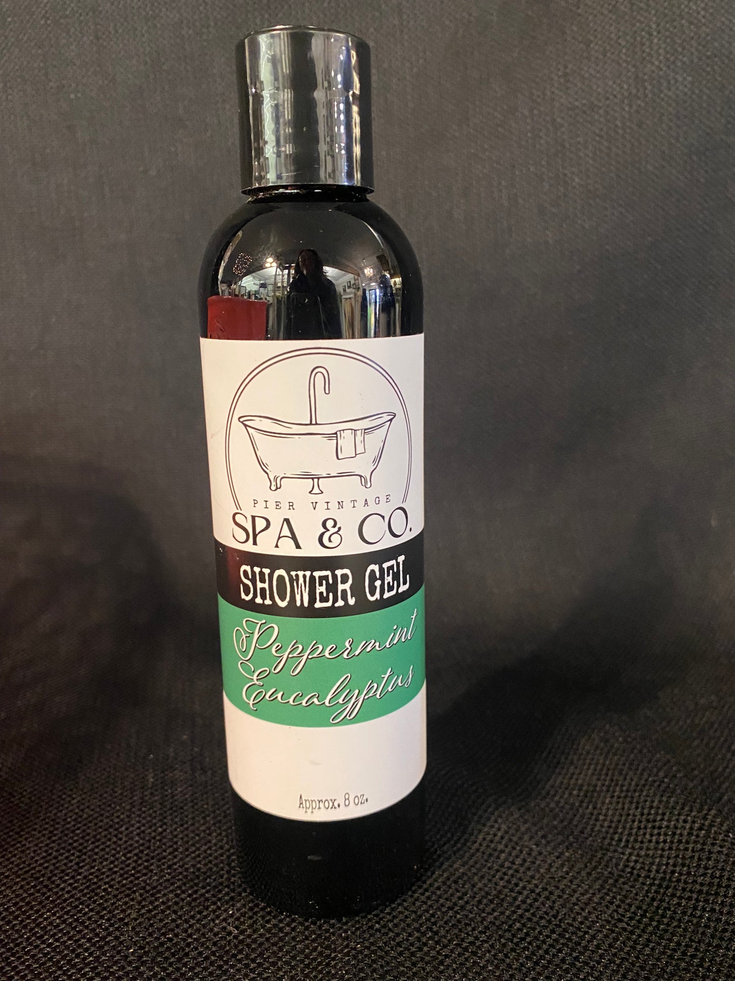 Bottle of Peppermint & Eucalyptus shower gel with a label on a dark background by Pier Vintage Spa & Co.