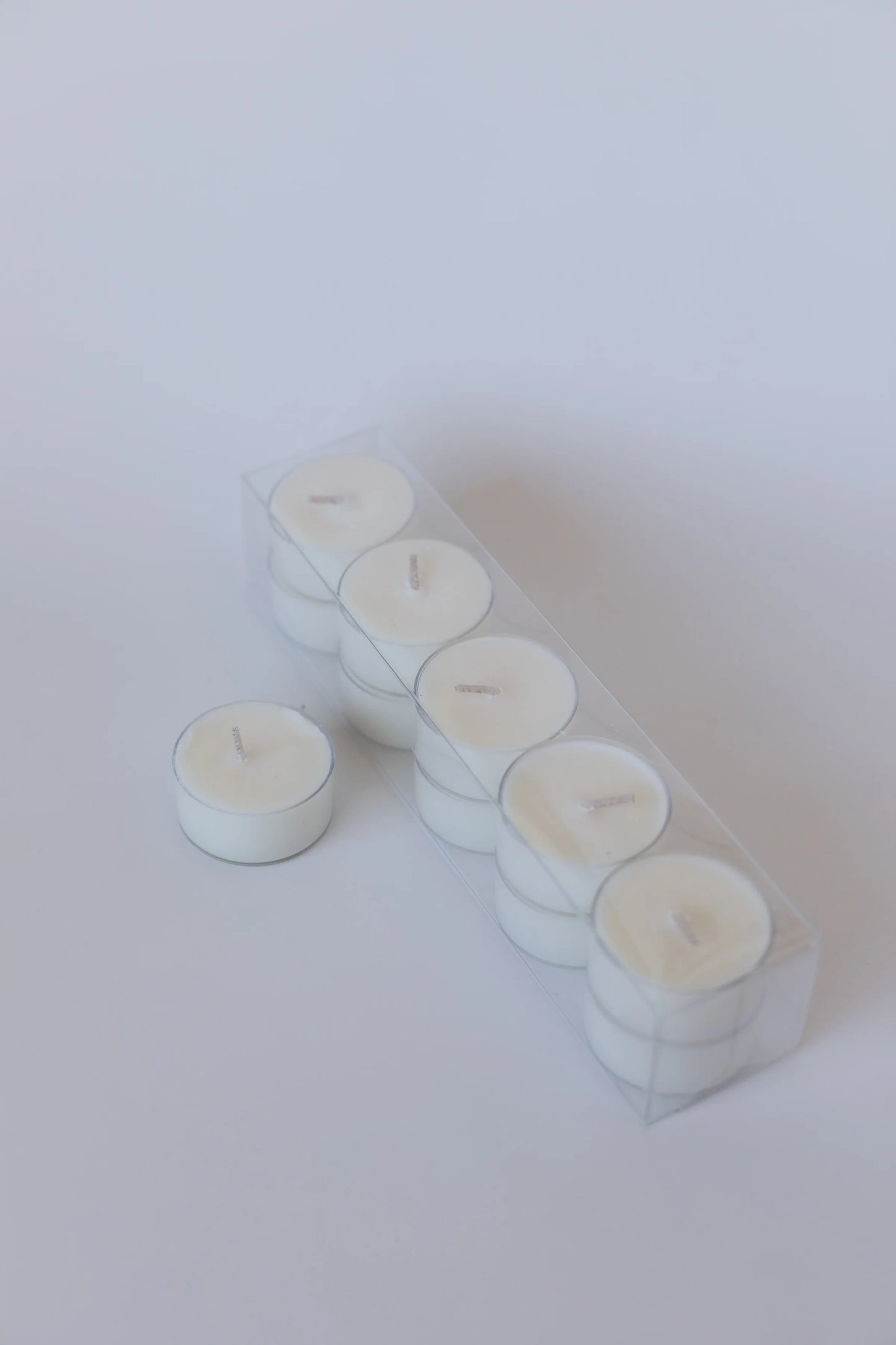 Set of white Lumiere de Bougie tea light candles in a clear box on a white background