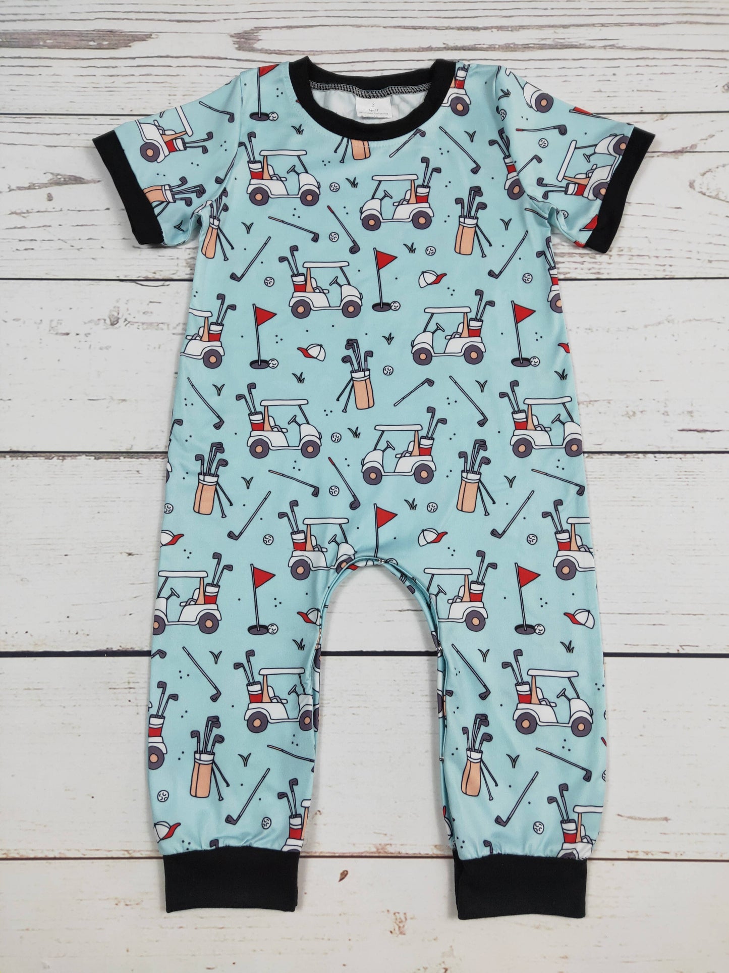 Children's onesie with golf-themed pattern on a wooden surface