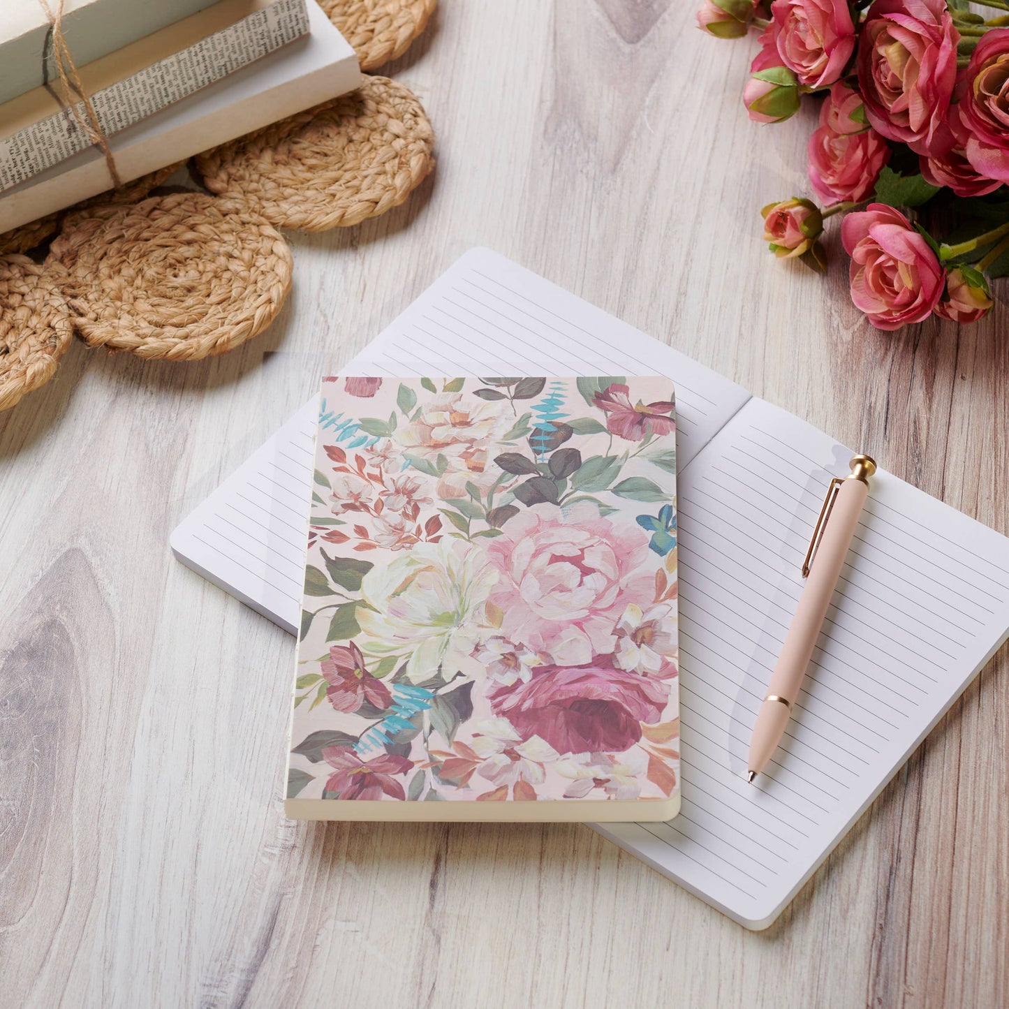 Floral notebook on a wooden surface with a pen and flowers