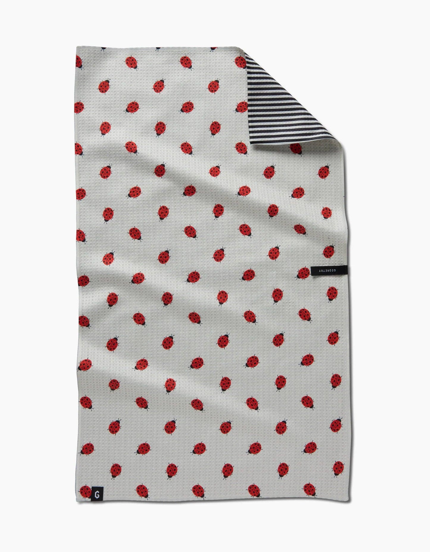 White towel with red pattern and black and white striped border on a white background