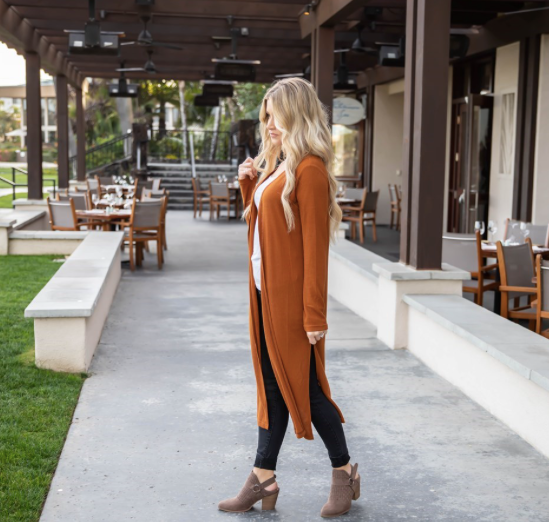 Woman walking outdoors in a casual setting with tables and chairs in the background