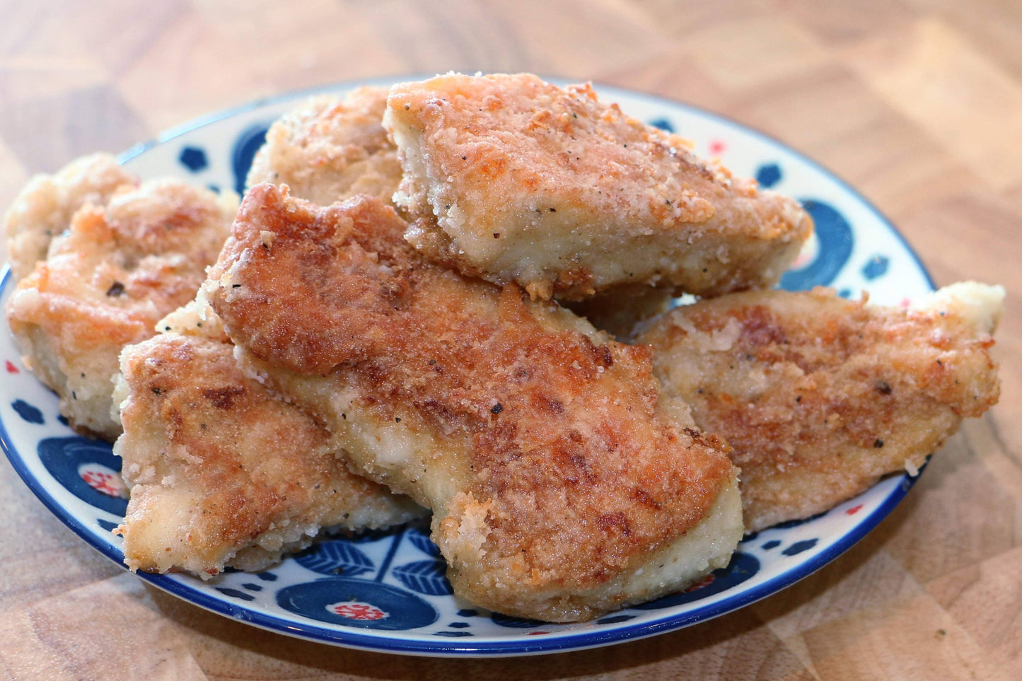 Breaded chicken wings on a decorative plate with a wooden background