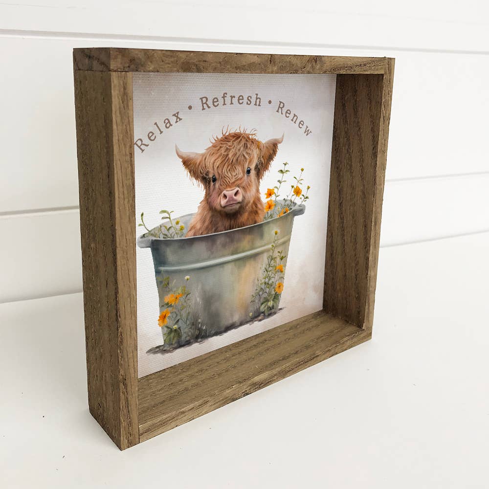 Framed picture of a Highland cow in a bathtub with flowers, text 'Relax Refresh Renew' above it.