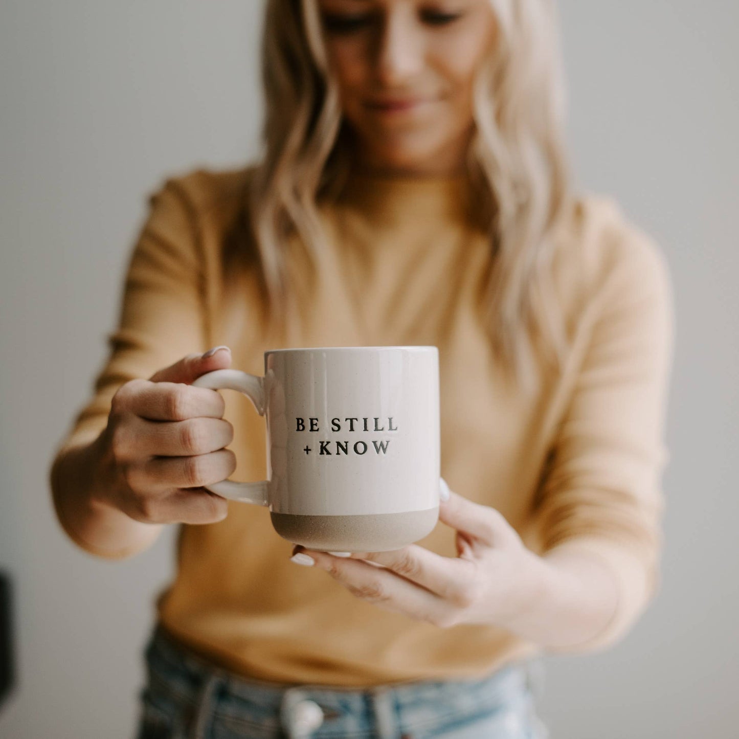 Person holding a mug with 'Be Still + Know' text