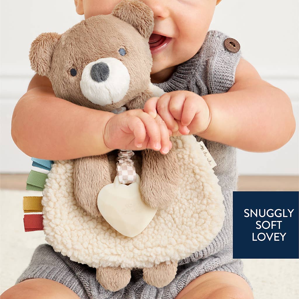Child holding a soft toy with text 'Snuggly Soft Lovey' on a light background