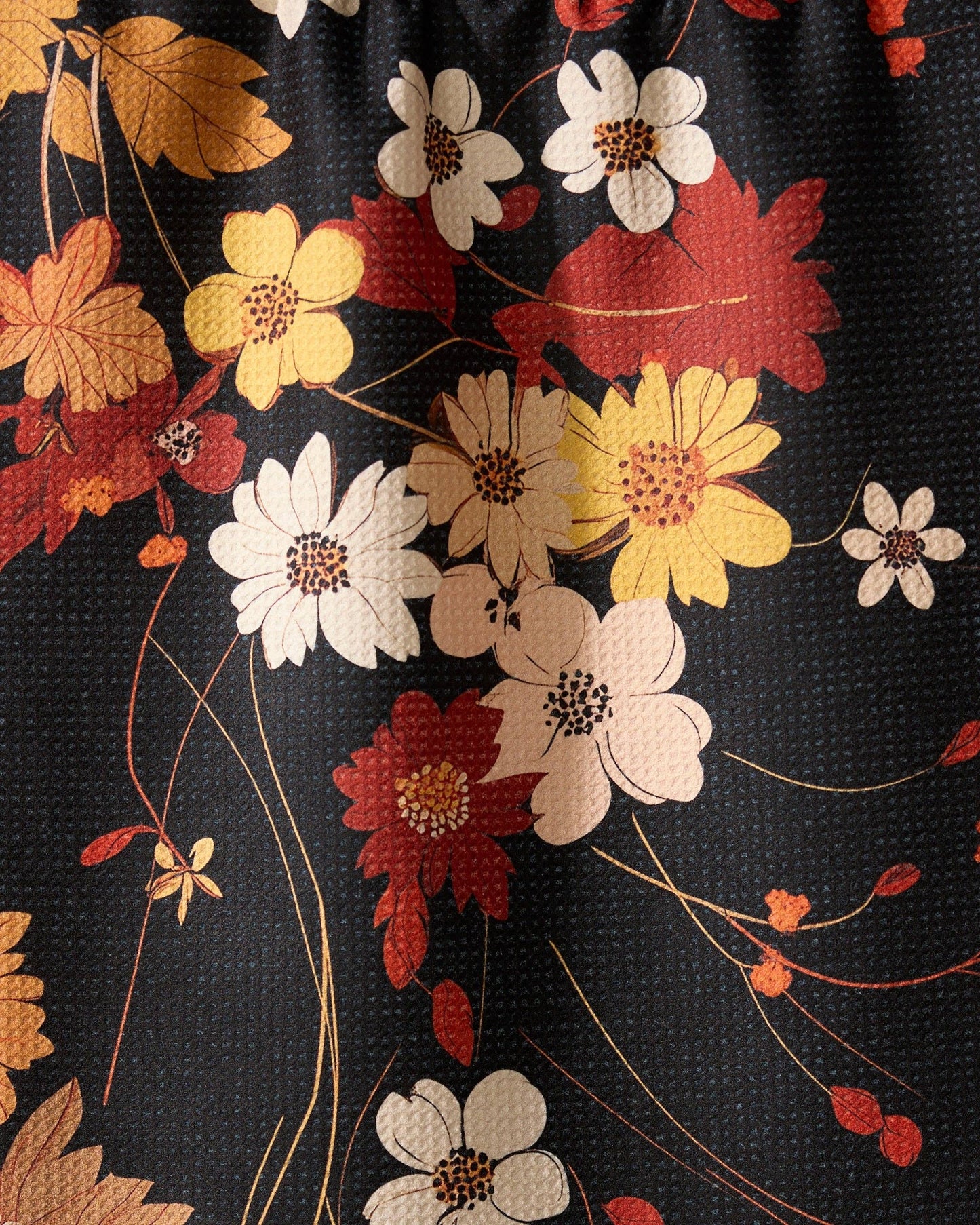 Geometry kitchen tea towel with close-up of floral fabric with red, yellow, and white flowers on a black background
