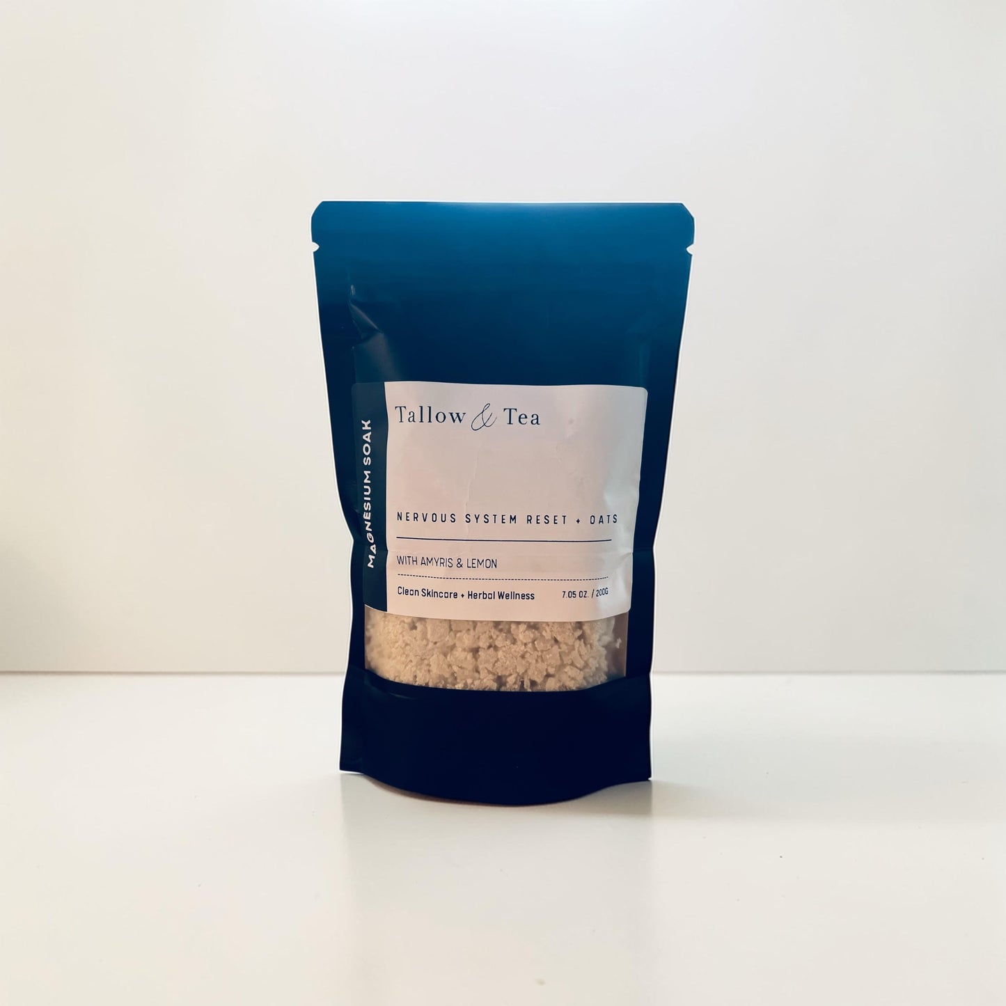 Black package of Tallow & Tea Mineral bath soak with a white label on a white background