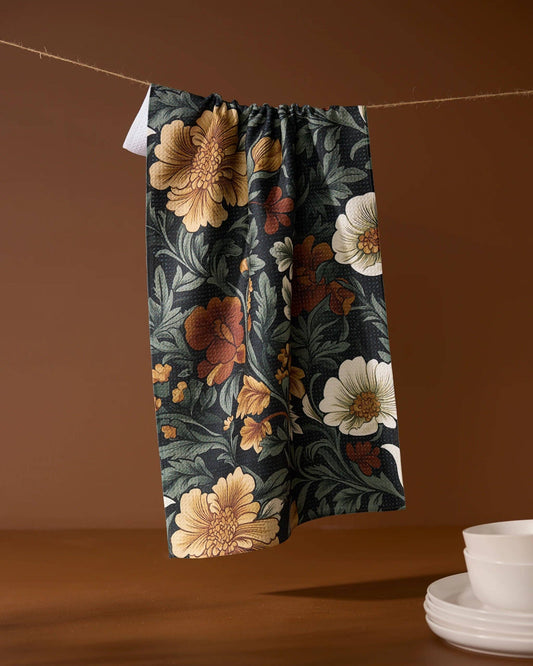Floral-patterned kitchen tea towel hanging on a line with a brown background Geometry brand