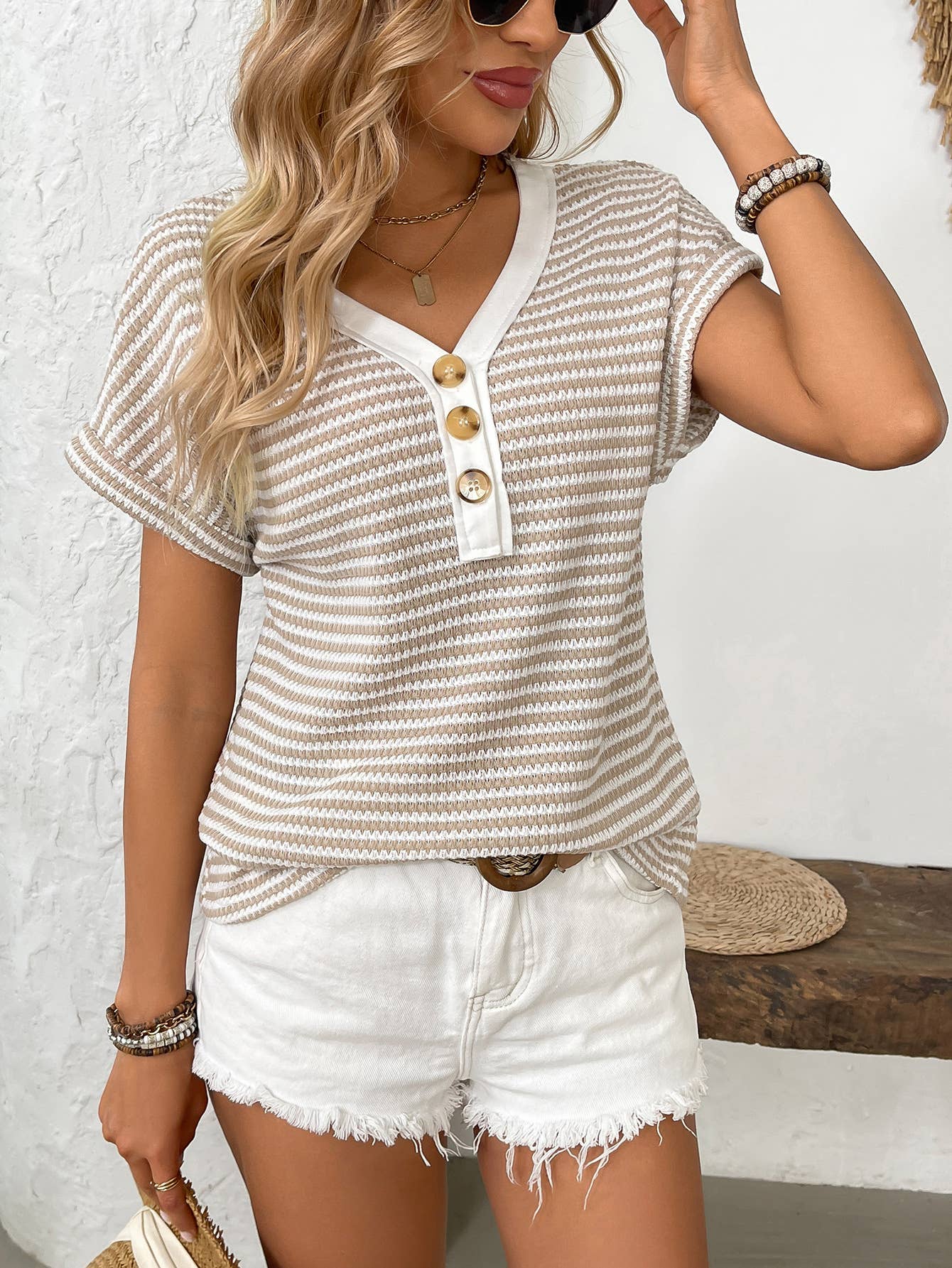 Woman wearing a striped shirt and white shorts with a neutral background
