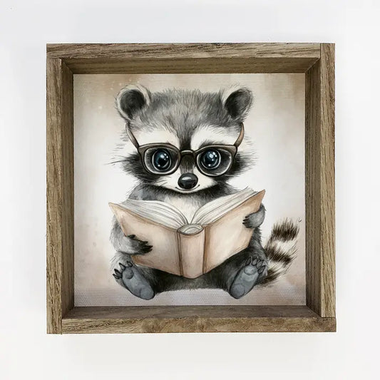Framed artwork of a raccoon wearing glasses and reading a book on a light background