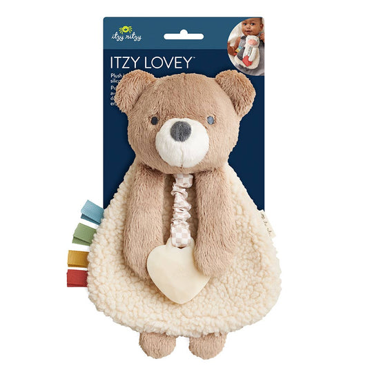 Plush teddy bear toy with heart and colorful strip in packaging on a white background