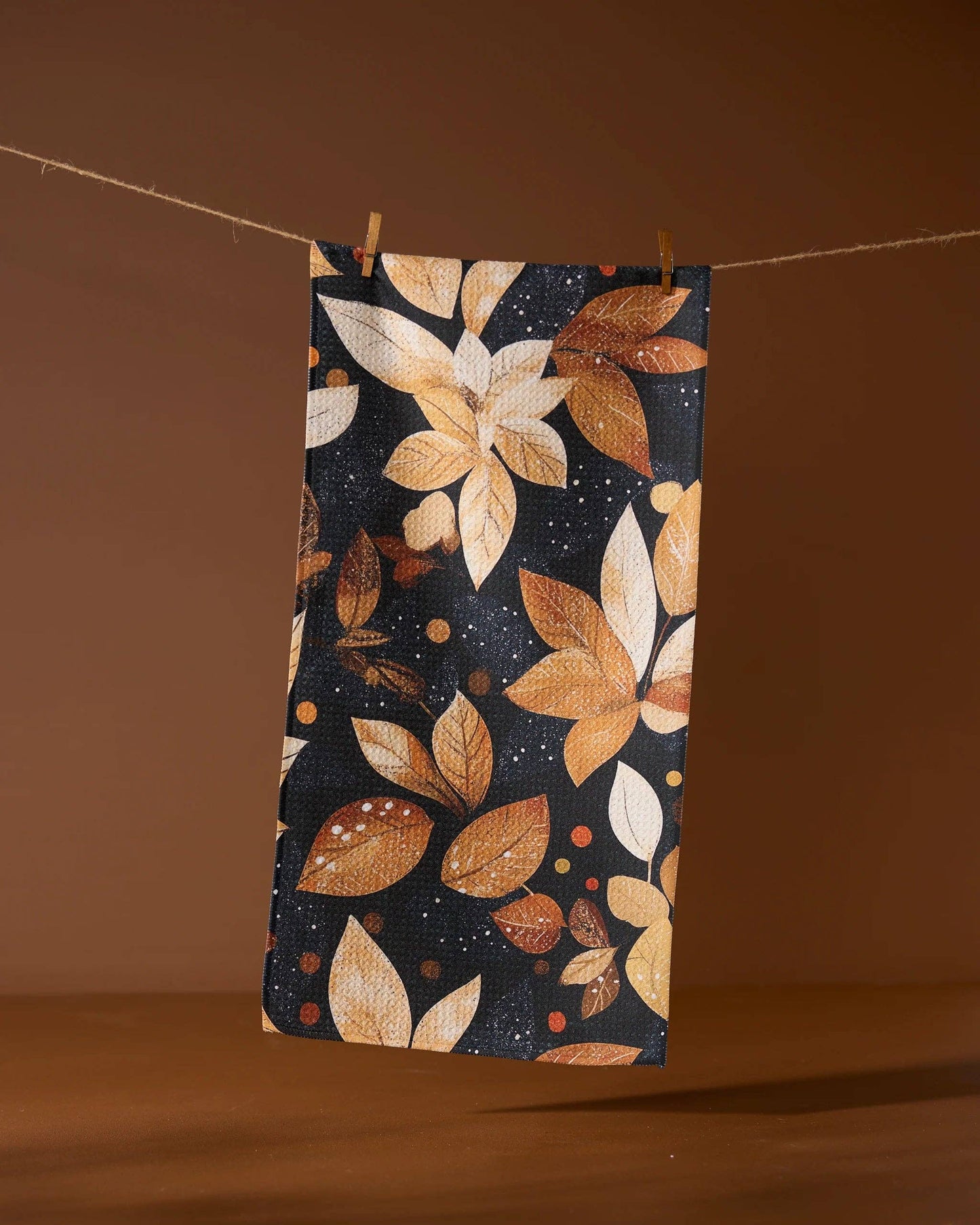 Geometry bar towel with autumn leaf pattern hanging on a line against a brown background