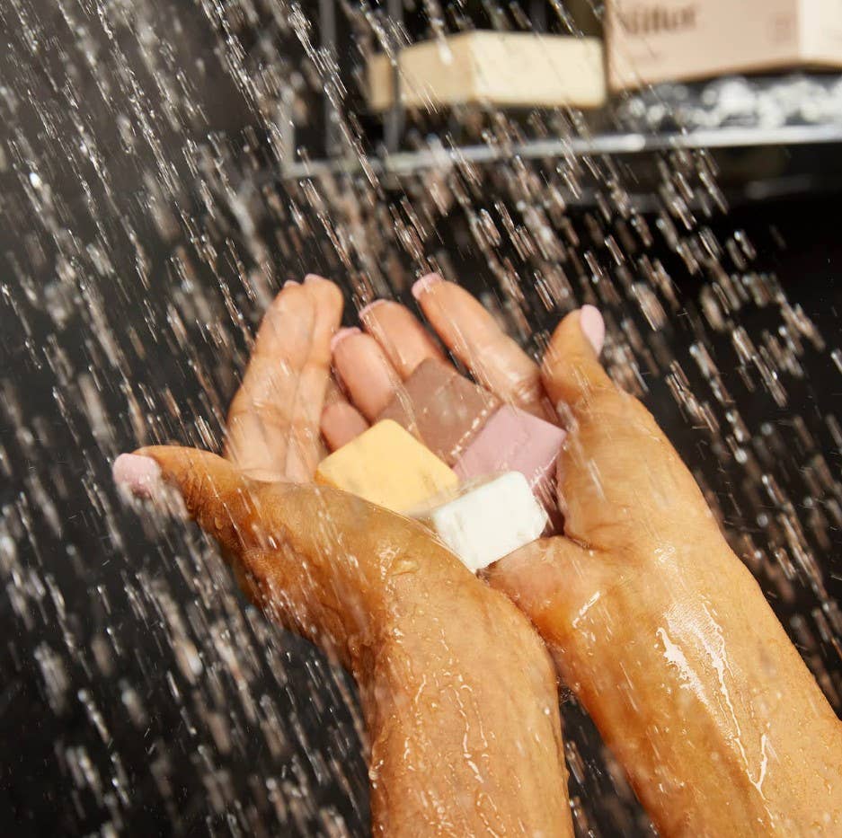 Close-up of hands under running water with soap bubbles, blurred background