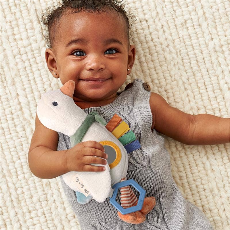 Baby holding a toy with colorful elements on a textured surface