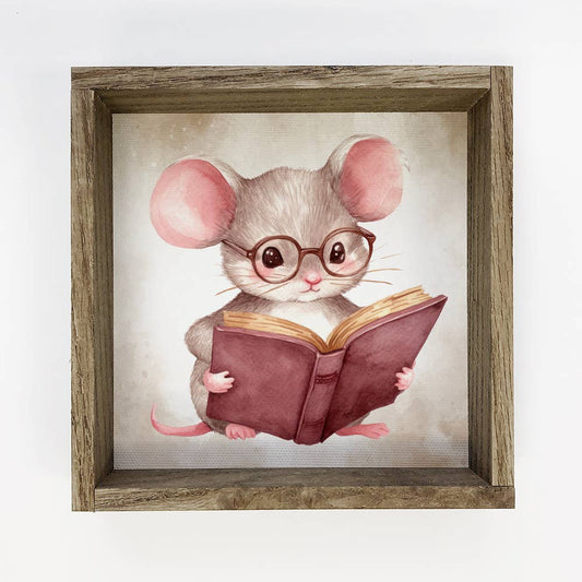 Illustration of a mouse wearing glasses and reading a book, framed in wood.