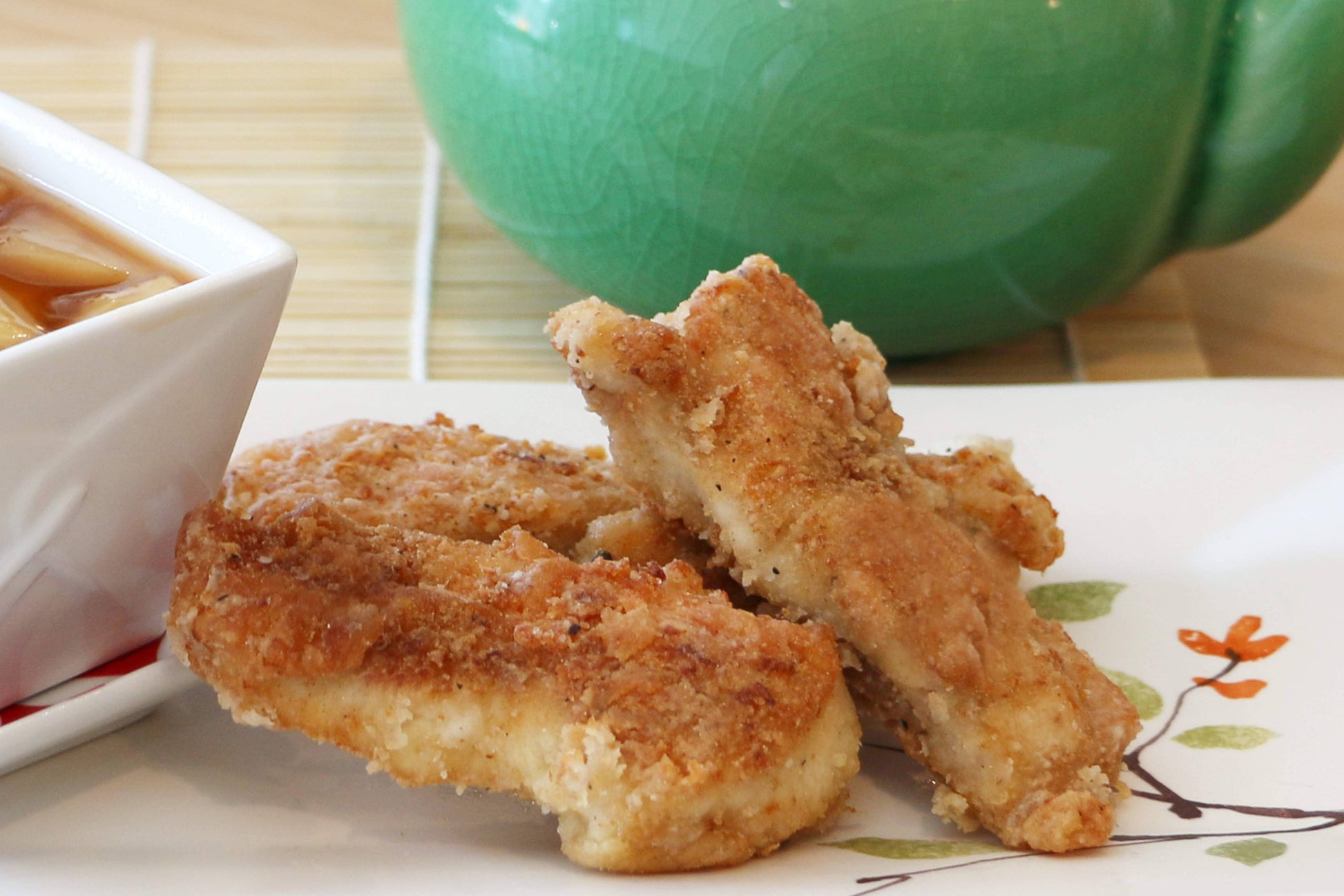 Fried chicken pieces on a plate with a green cup in the background