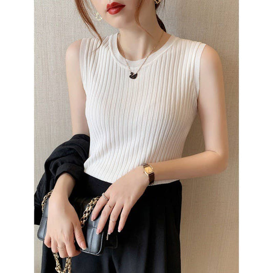 Woman wearing a white sleeveless top and black skirt, holding a clutch.