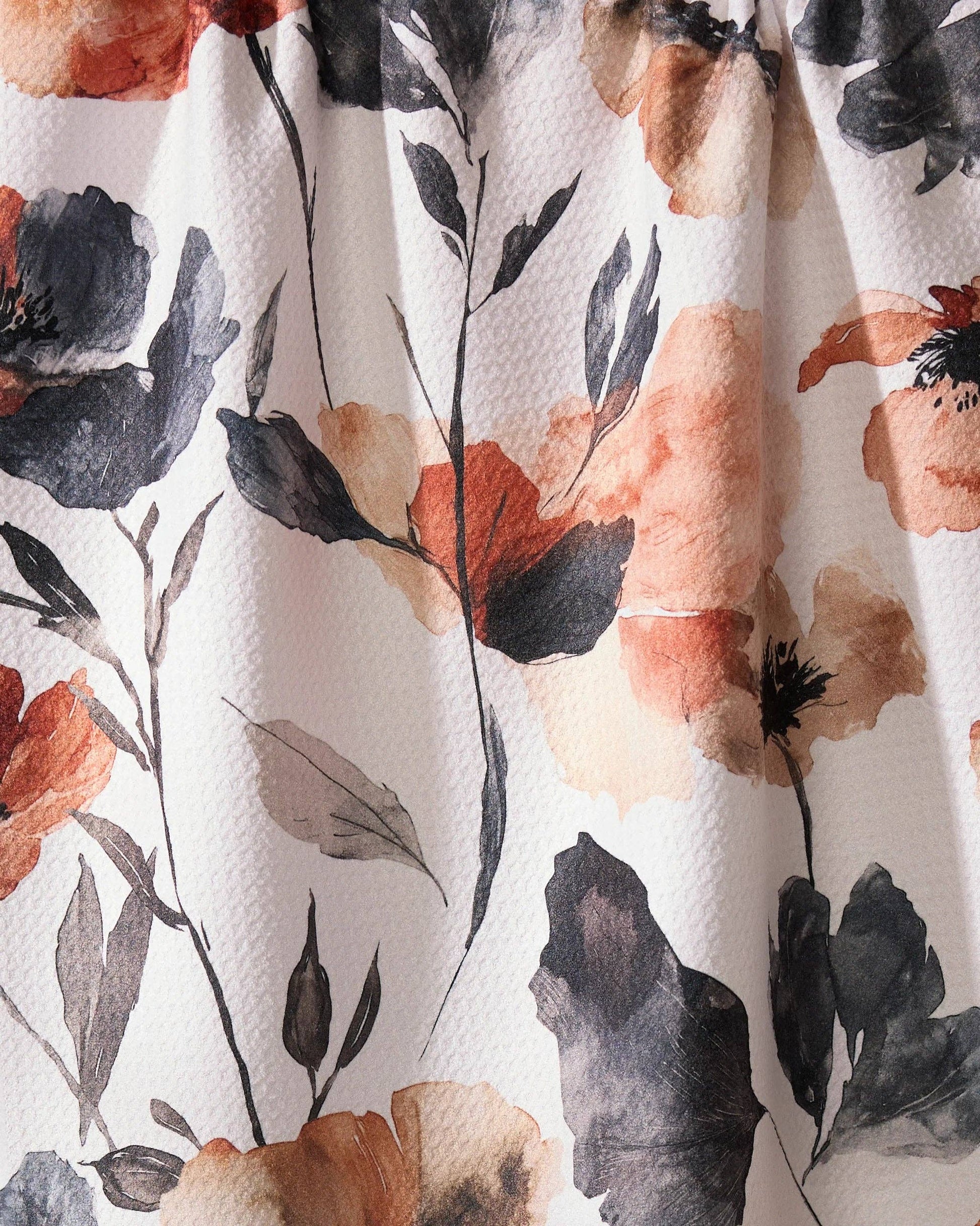Geometry brand kitchen tea towel with floral pattern with orange, black, and beige flowers on a white background