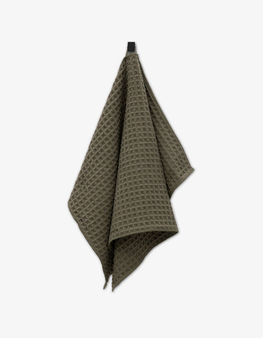 A forest green waffle hand towel with a textured pattern, made of recycled materials.