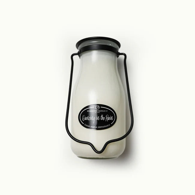 White candle in a glass jar with a black lid on a white background