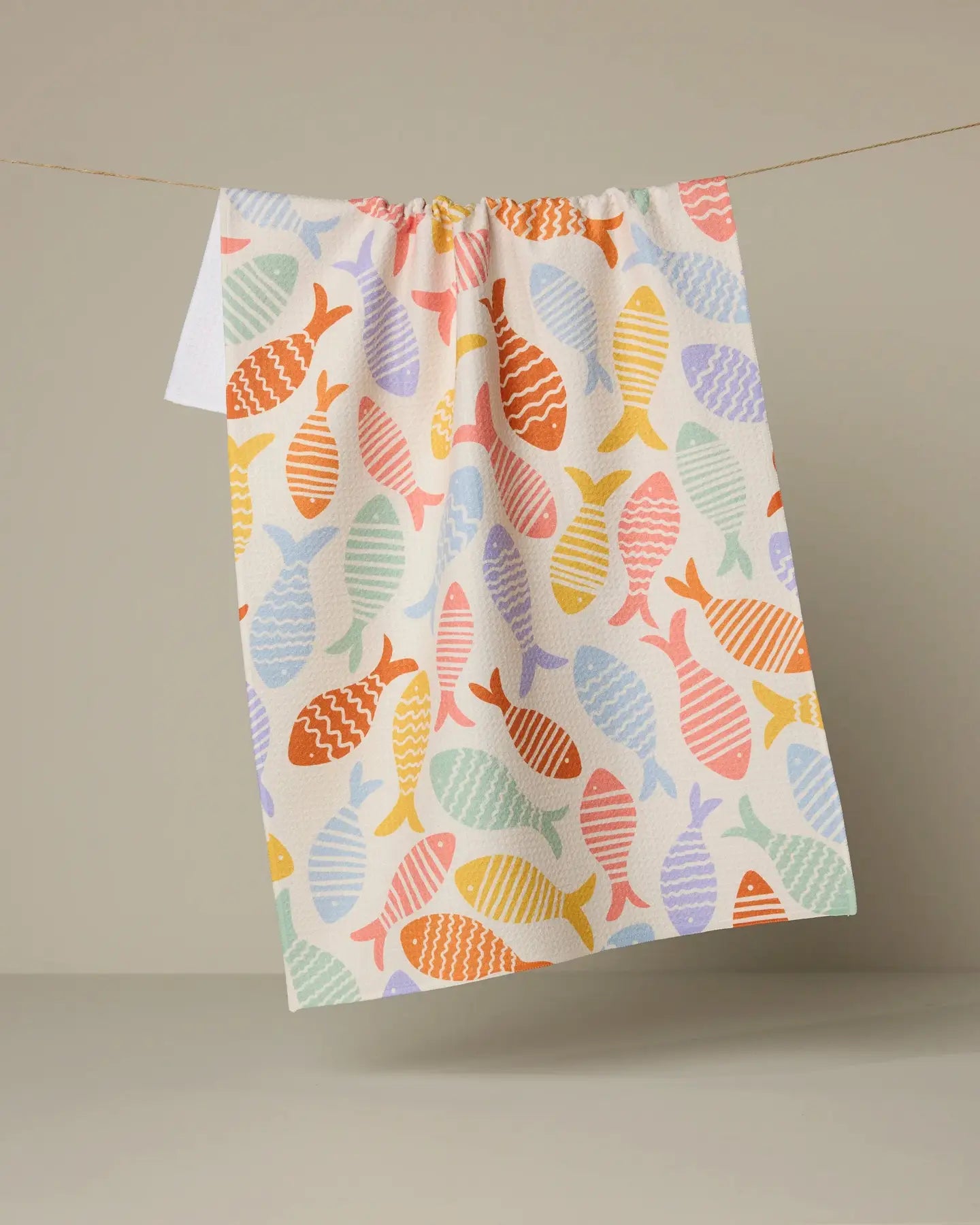 Colorful fish-patterned Geometry tea towel hanging on a line against a neutral background