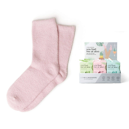 A pair of pink spa socks displayed alongside a color assortment pack with blue and green socks, labeled 'You Had Me At Aloe'.