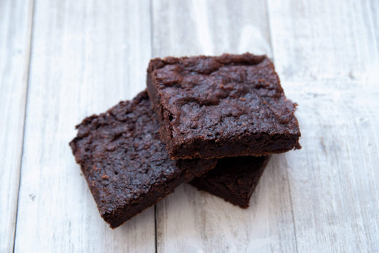 Two brownies on a light wooden surface