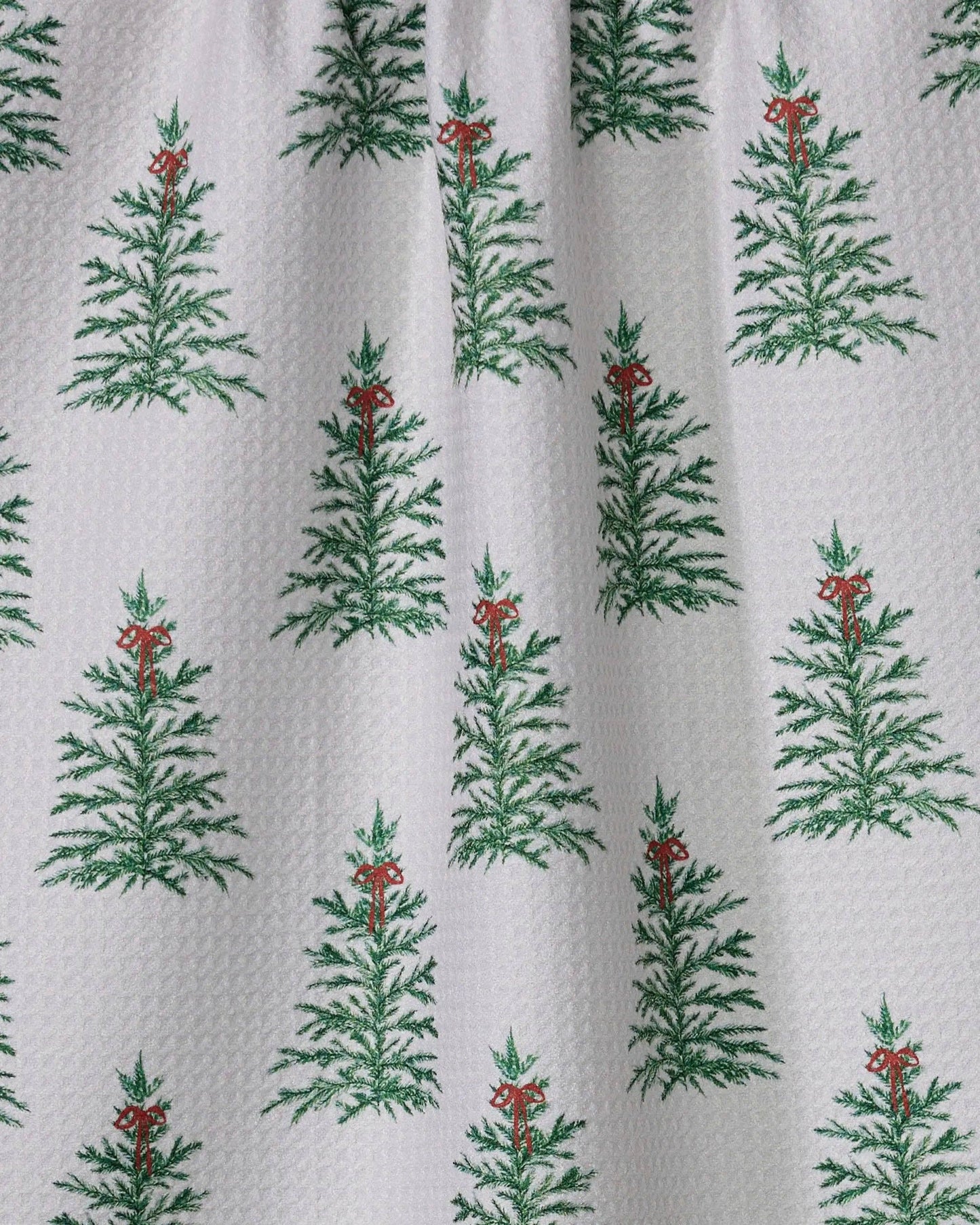 Geometry Tea Towel l with green tree pattern hanging on a line against a green background