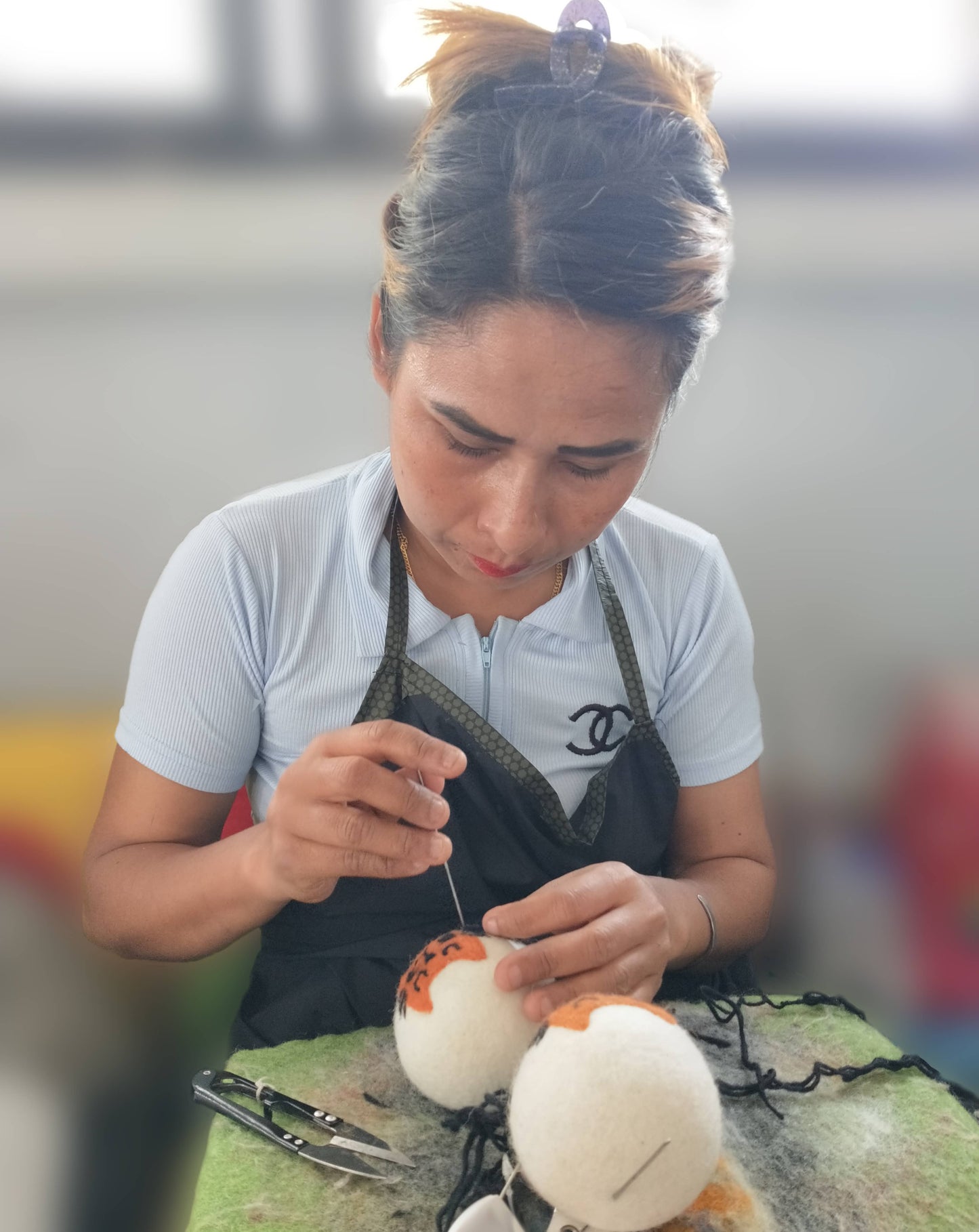 Person working on a wool dryer ball design with a blurred background