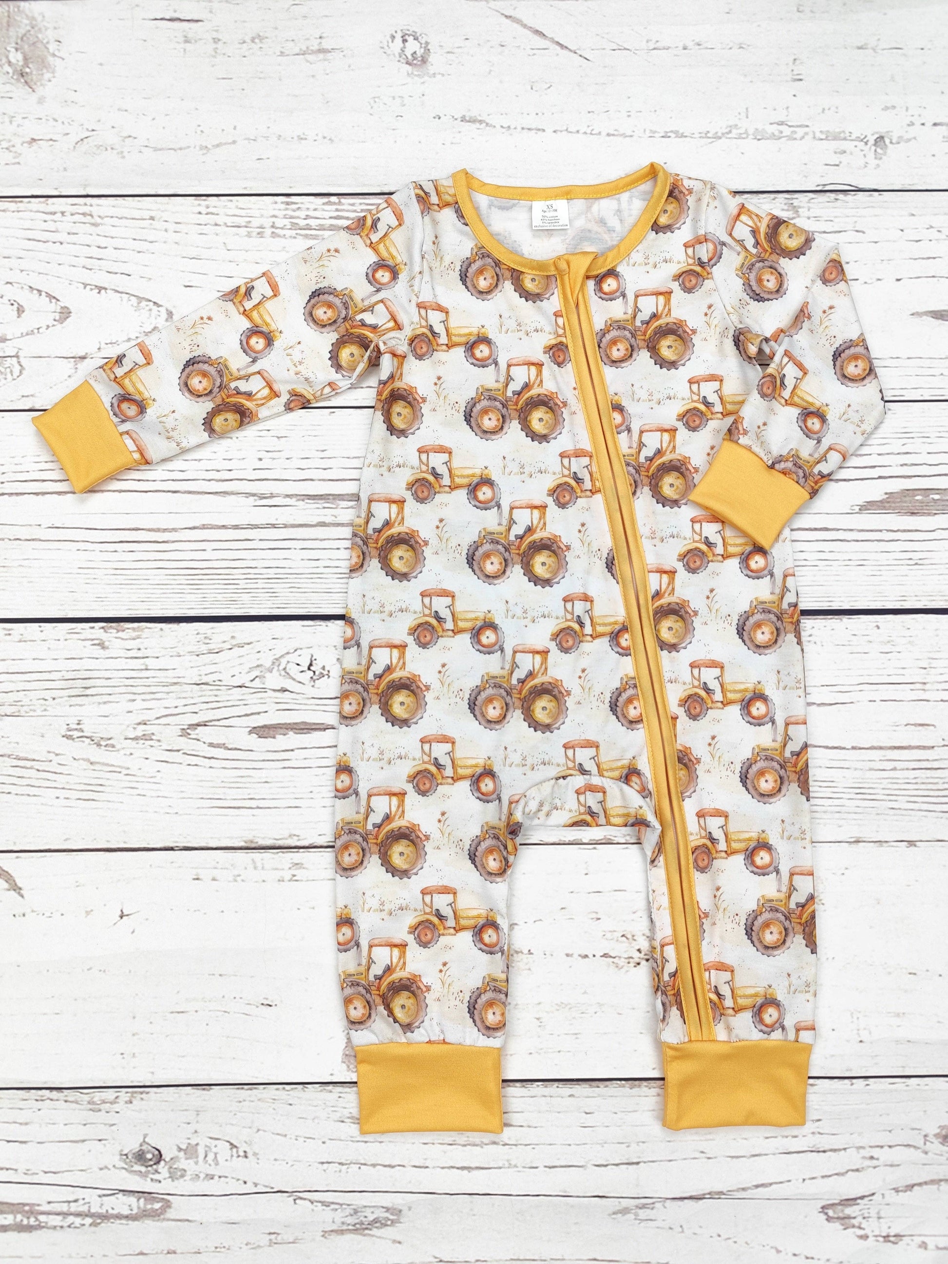 Baby onesie with tractor pattern on a wooden surface