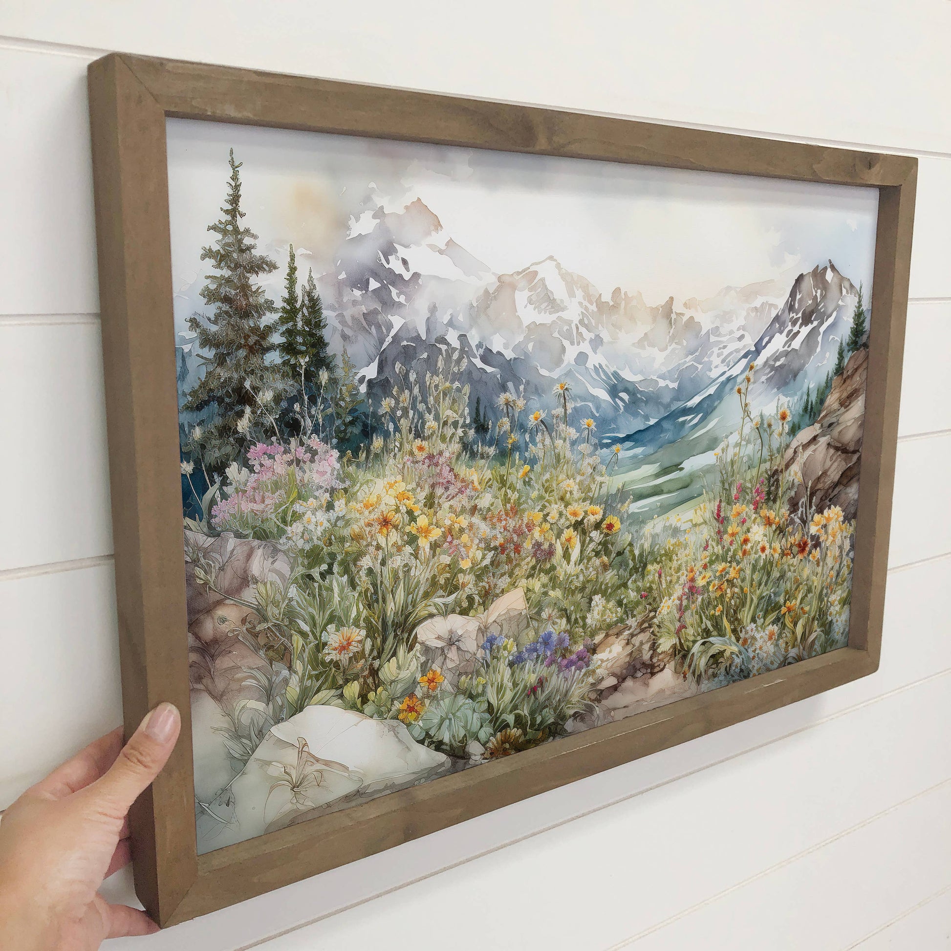 Framed artwork of a mountain landscape with flowers and a rabbit.
