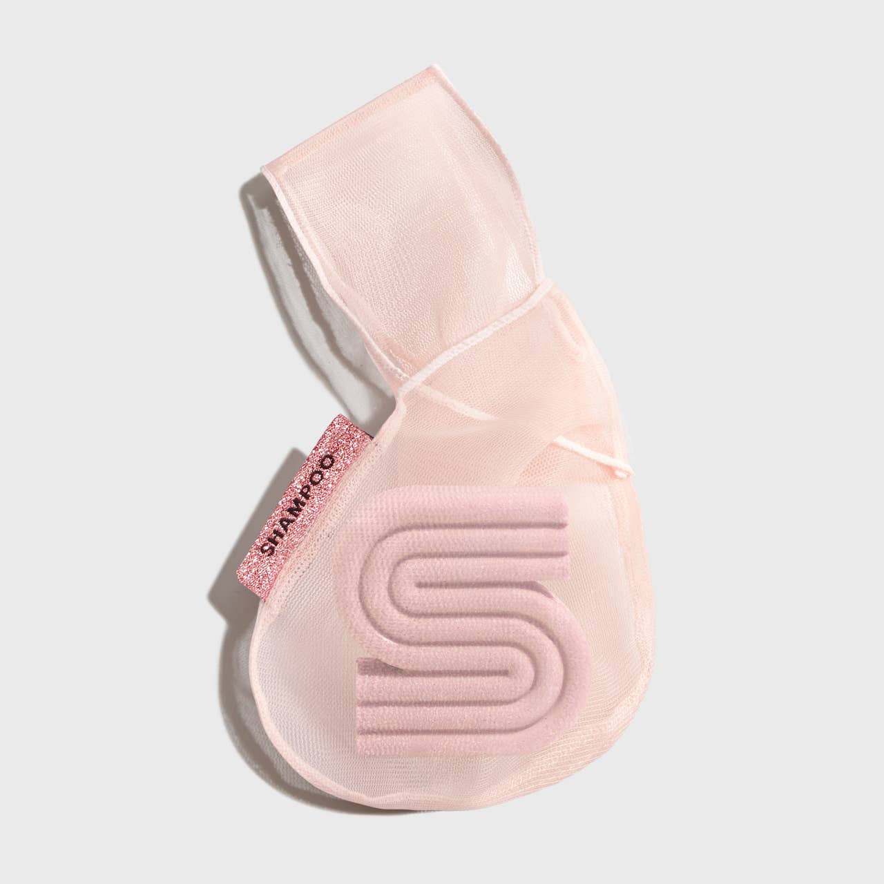 A blush pink mesh fabric shampoo beauty bar bag with a transparent window displaying the product. It is packaged with a product card that has text including the brand name and product description.