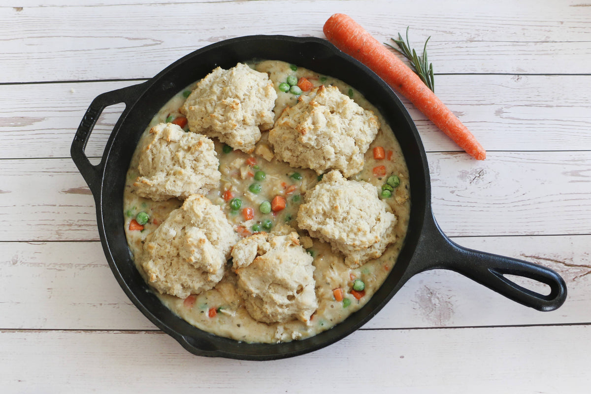 Skillet with chicken and dumplings on a wooden surface
